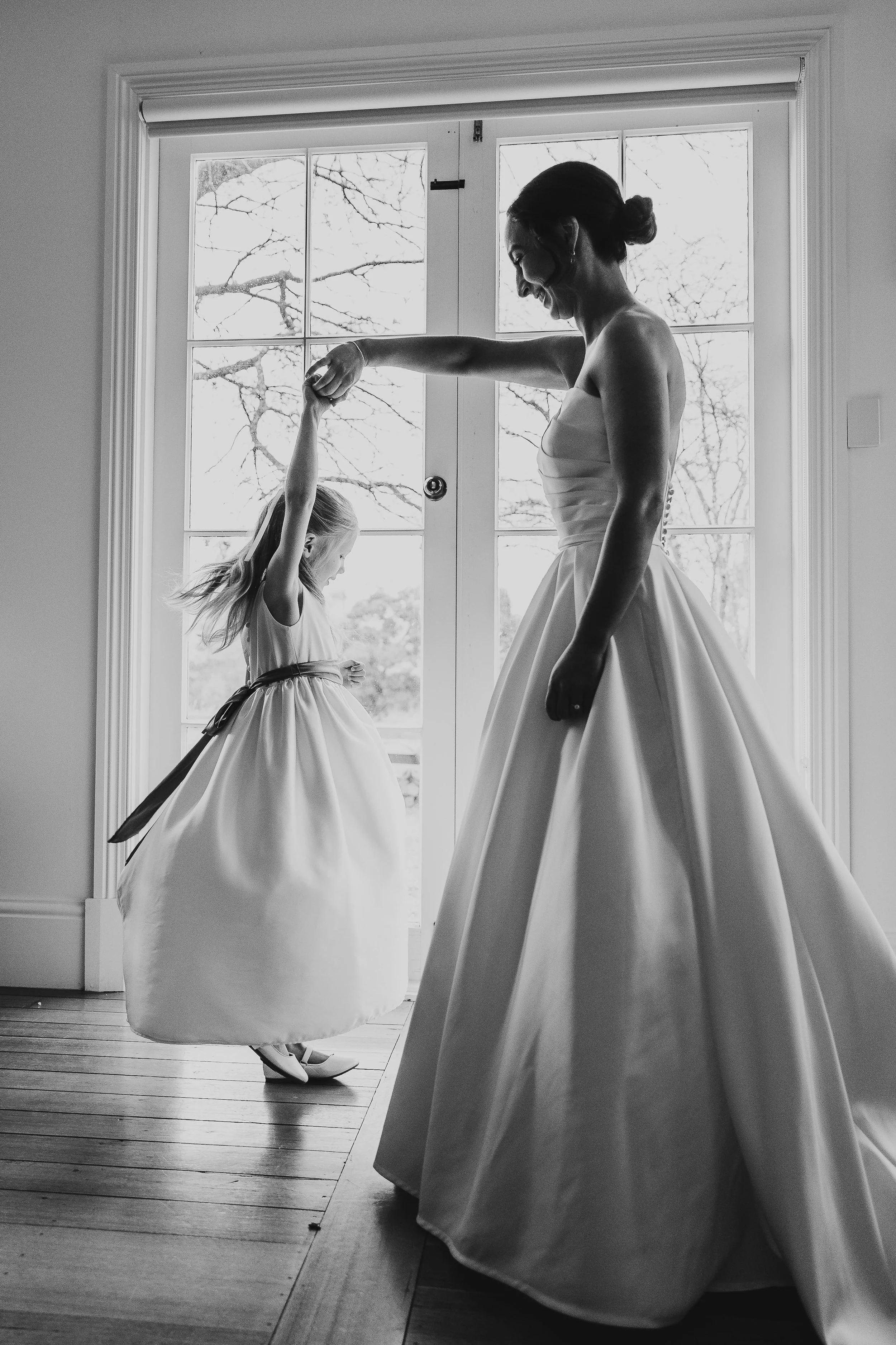 Bride and flower girl spinning around in lounge room