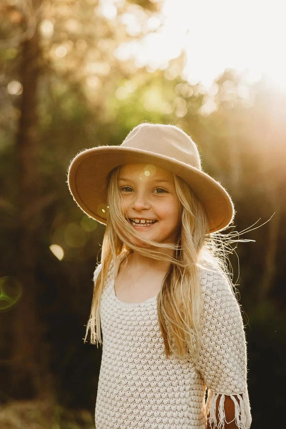 girl smiling at camera with pink hat in golden light
