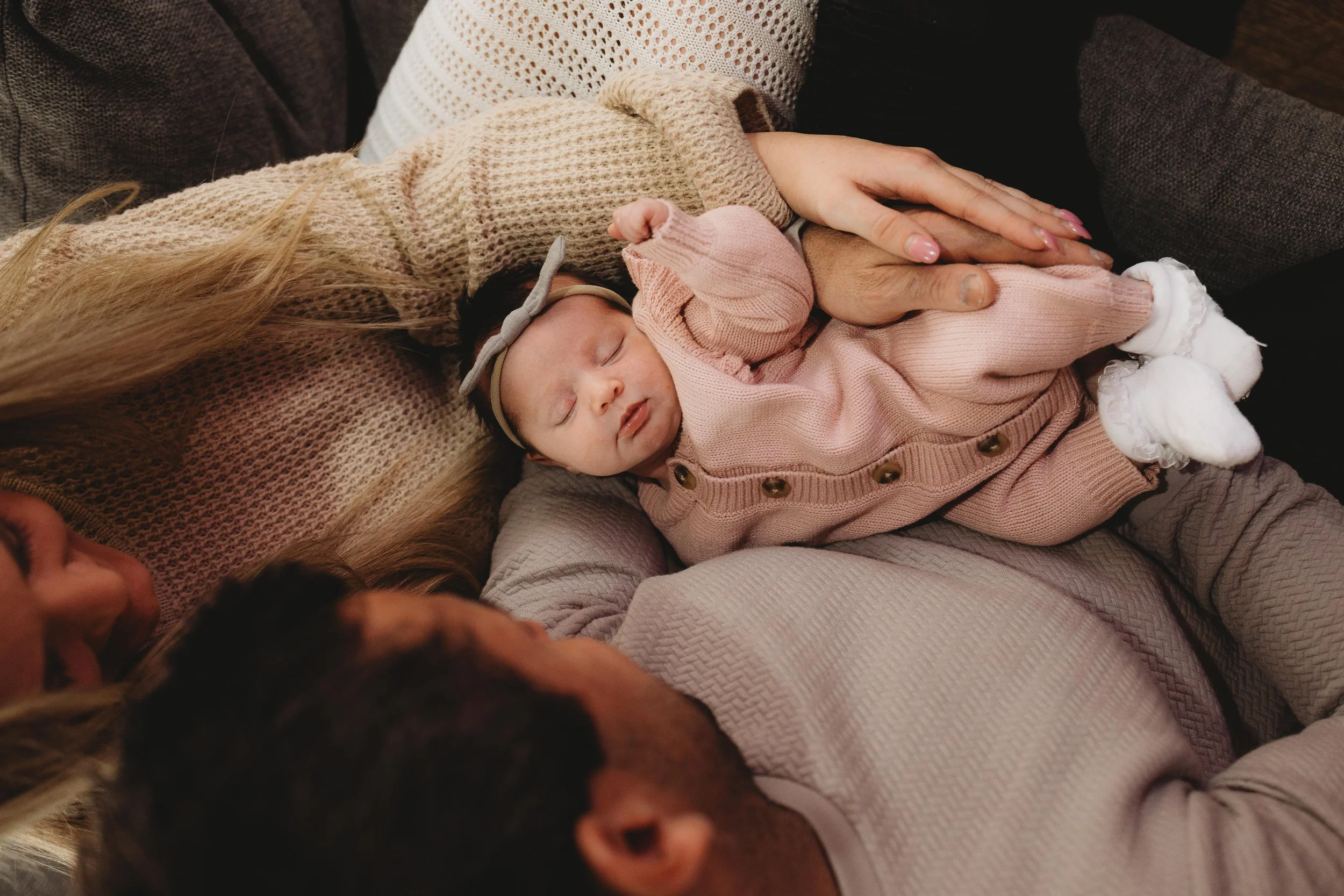 newborn baby girls on couch snuggled up on couch with parents