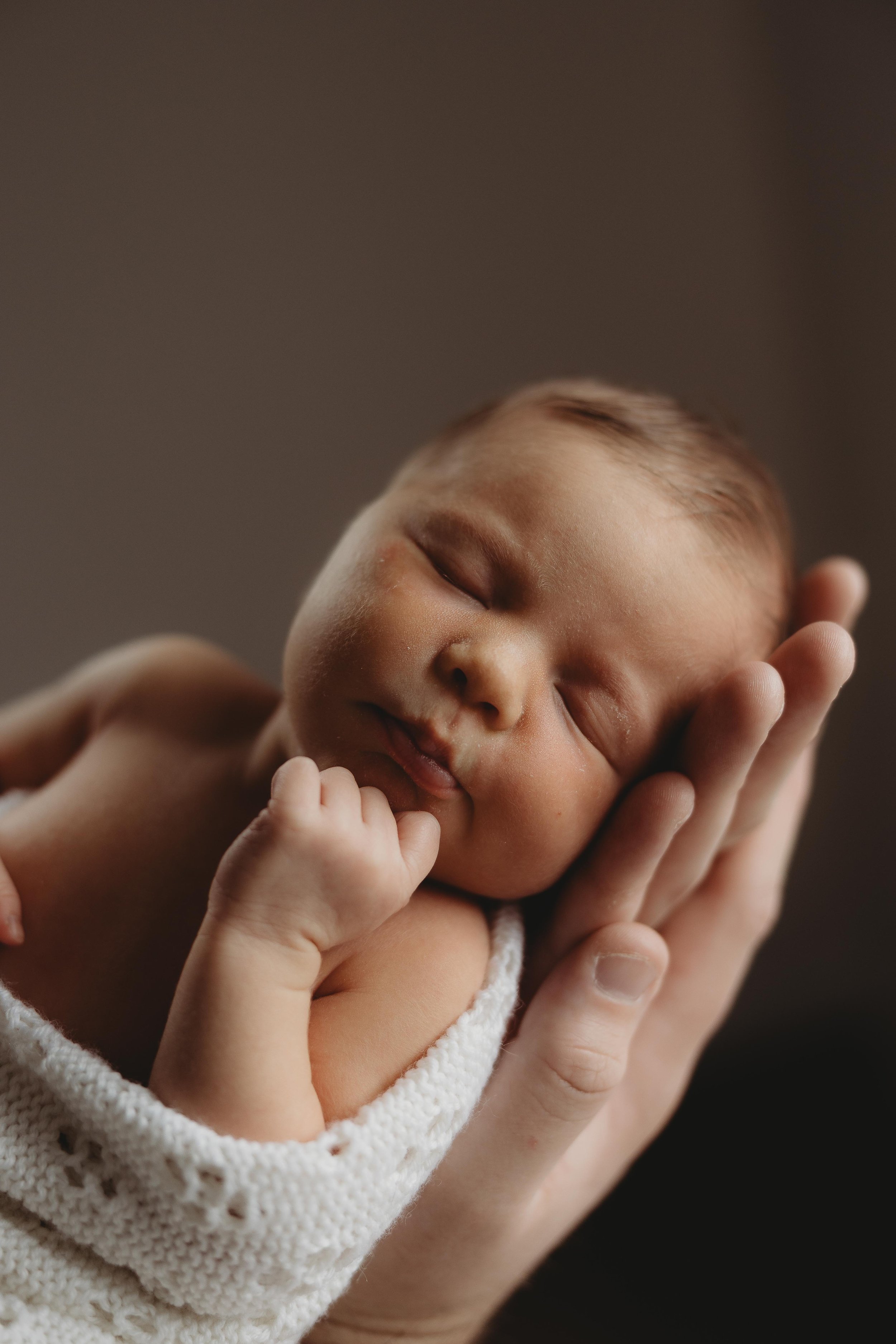 newborn baby held in dads arms