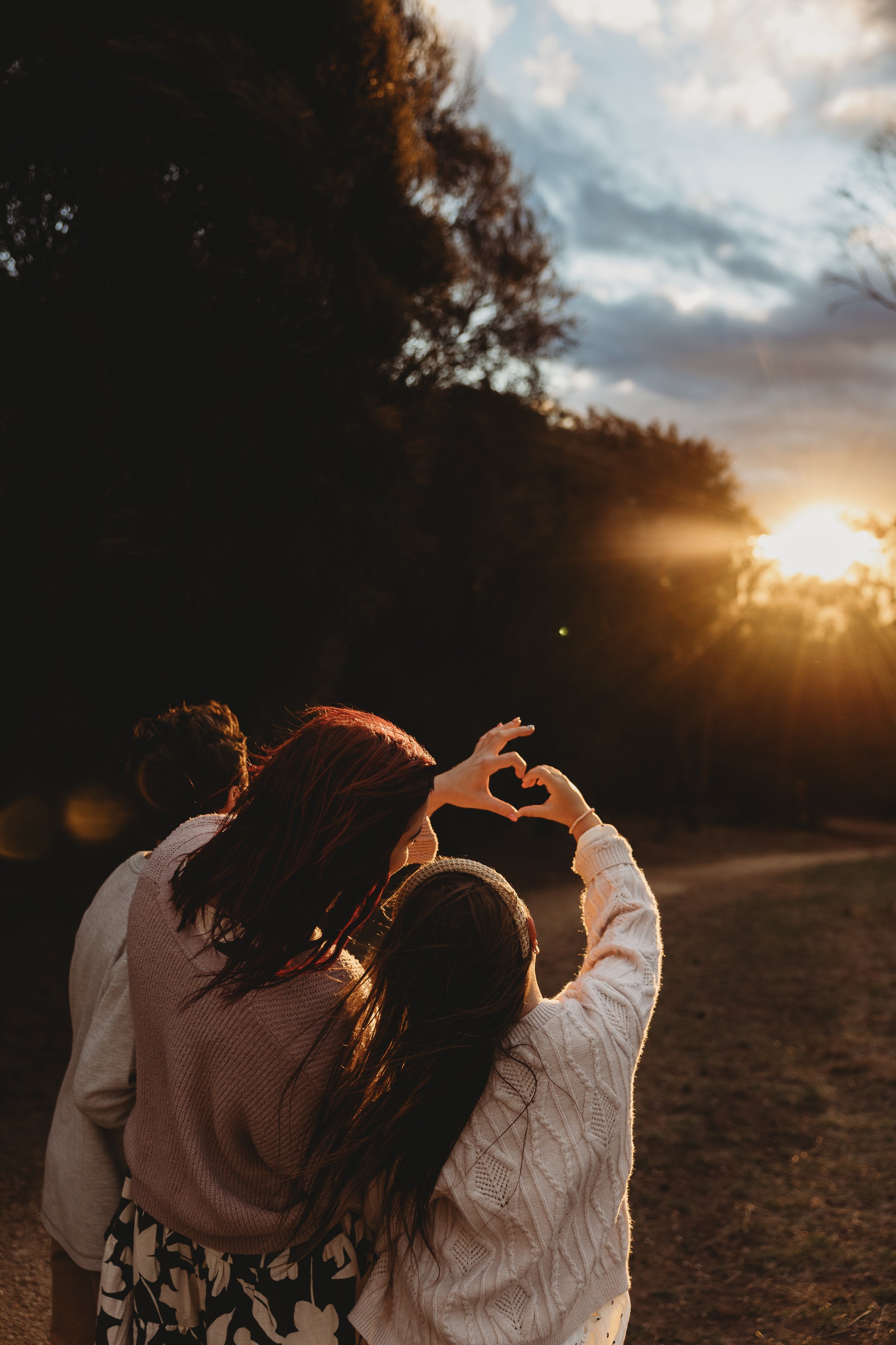 mum and children looking at the sun making a heart shap with hands into the sunlight