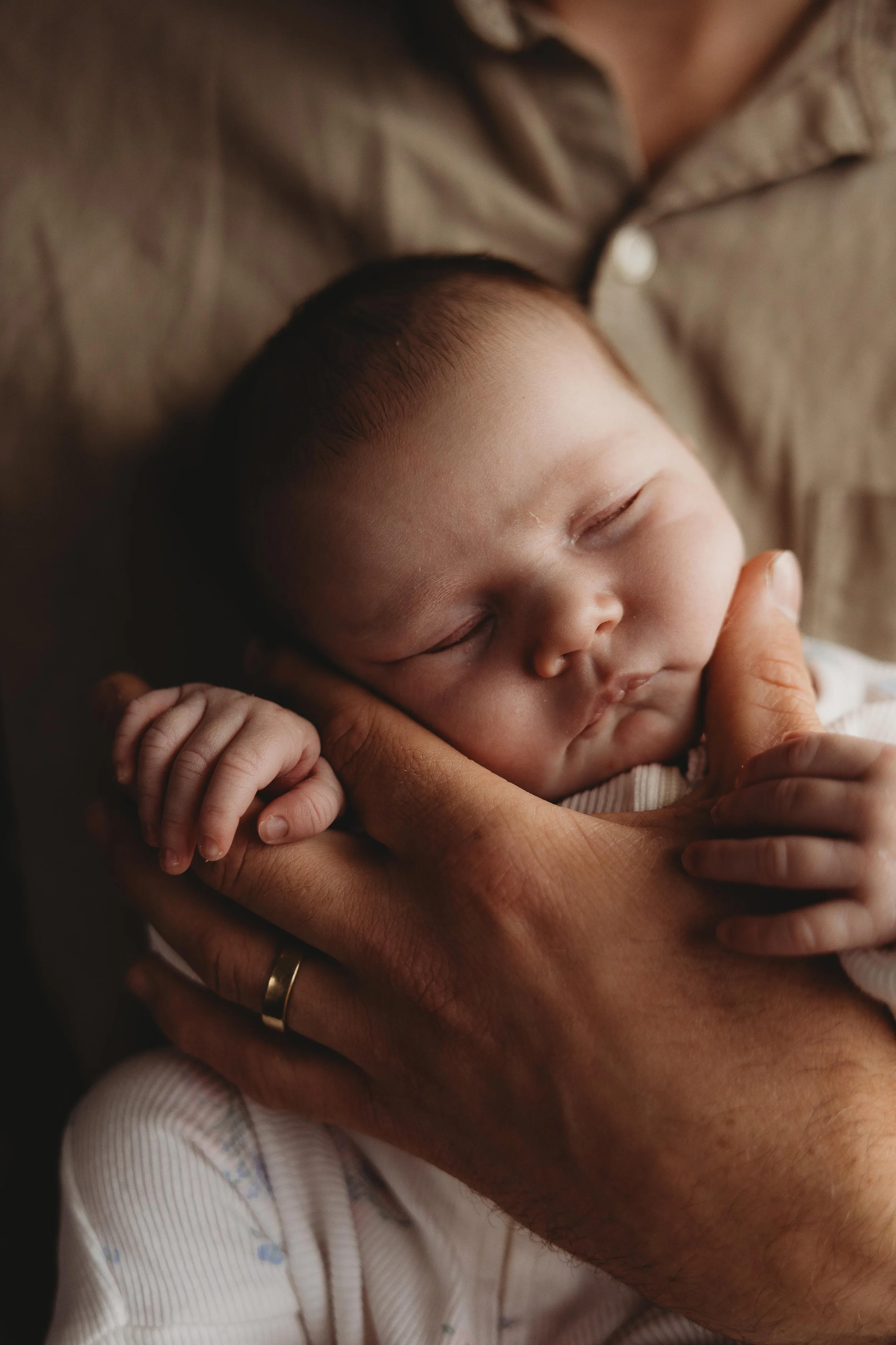 newborn baby being held close in dad arm