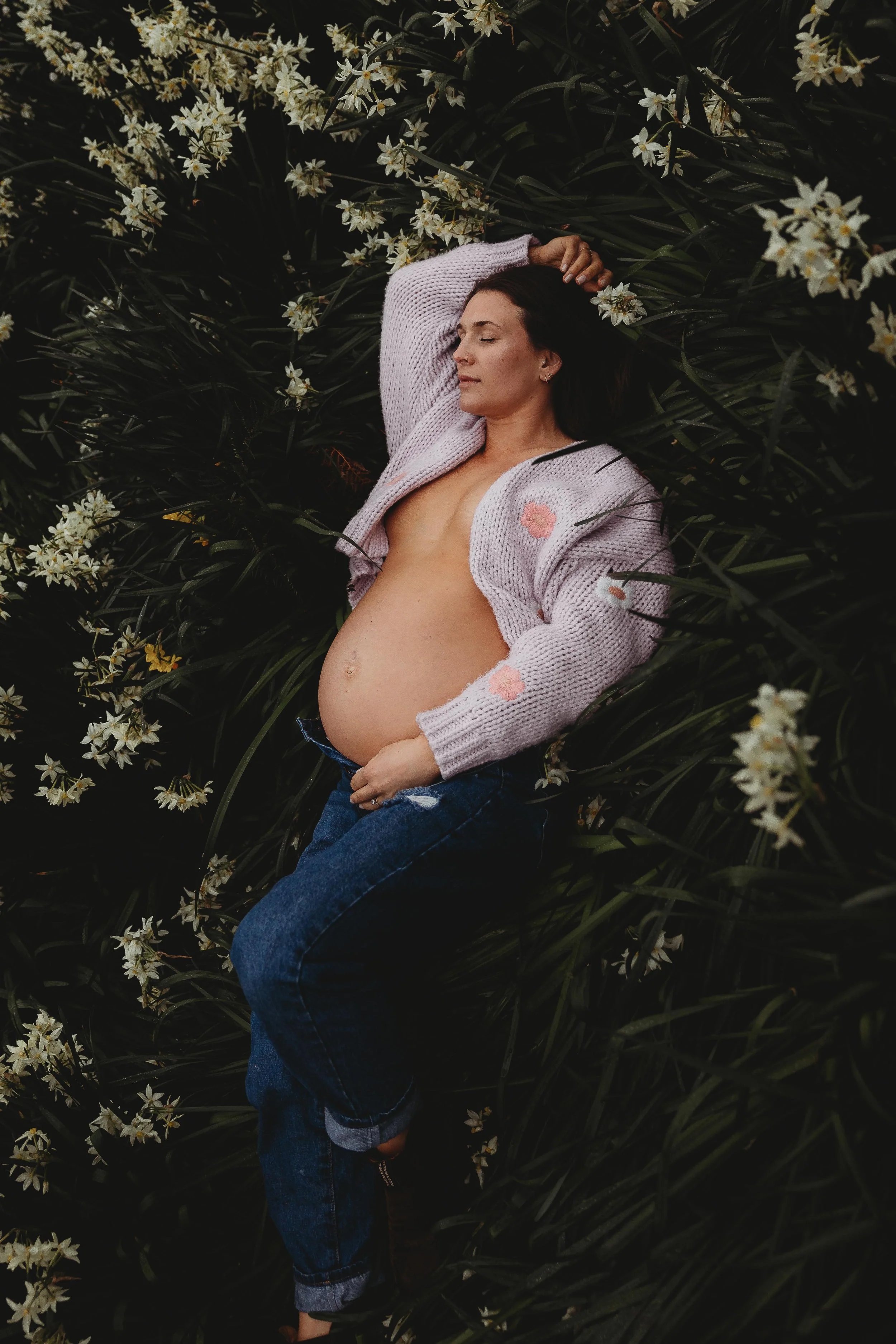 Pregnant woman laying in field of flowers