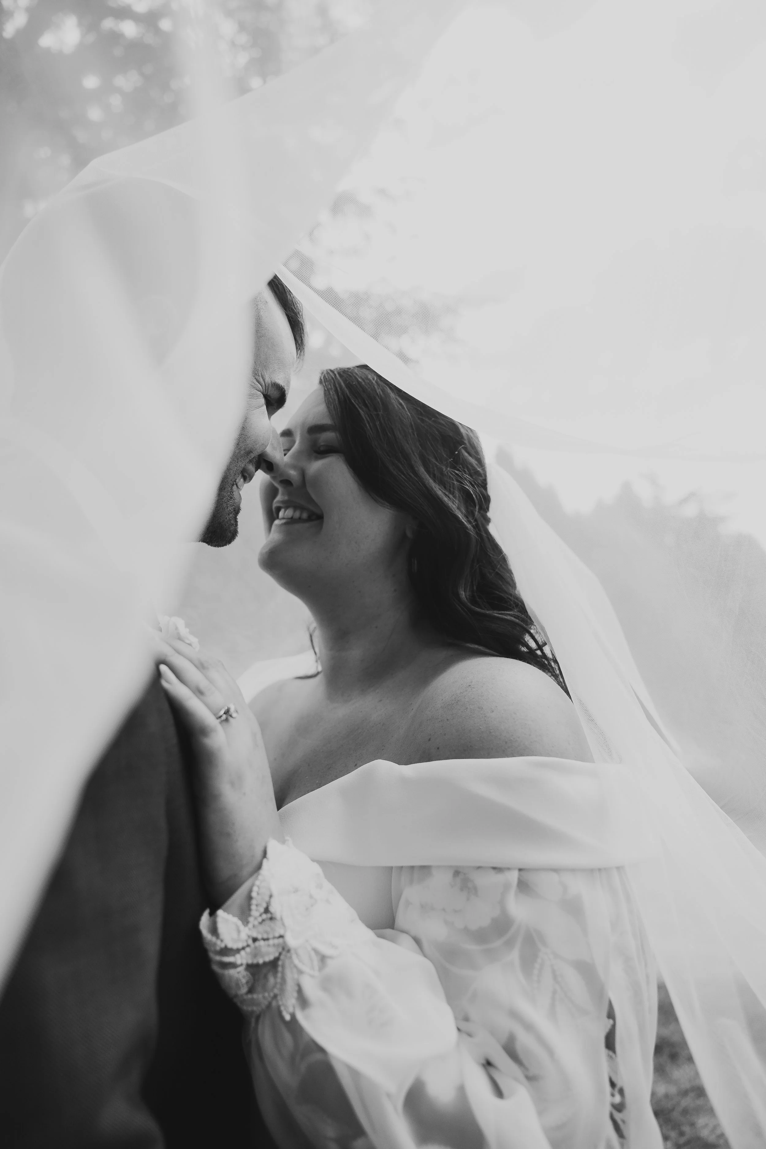 bride and groom embracing under wedding vail
