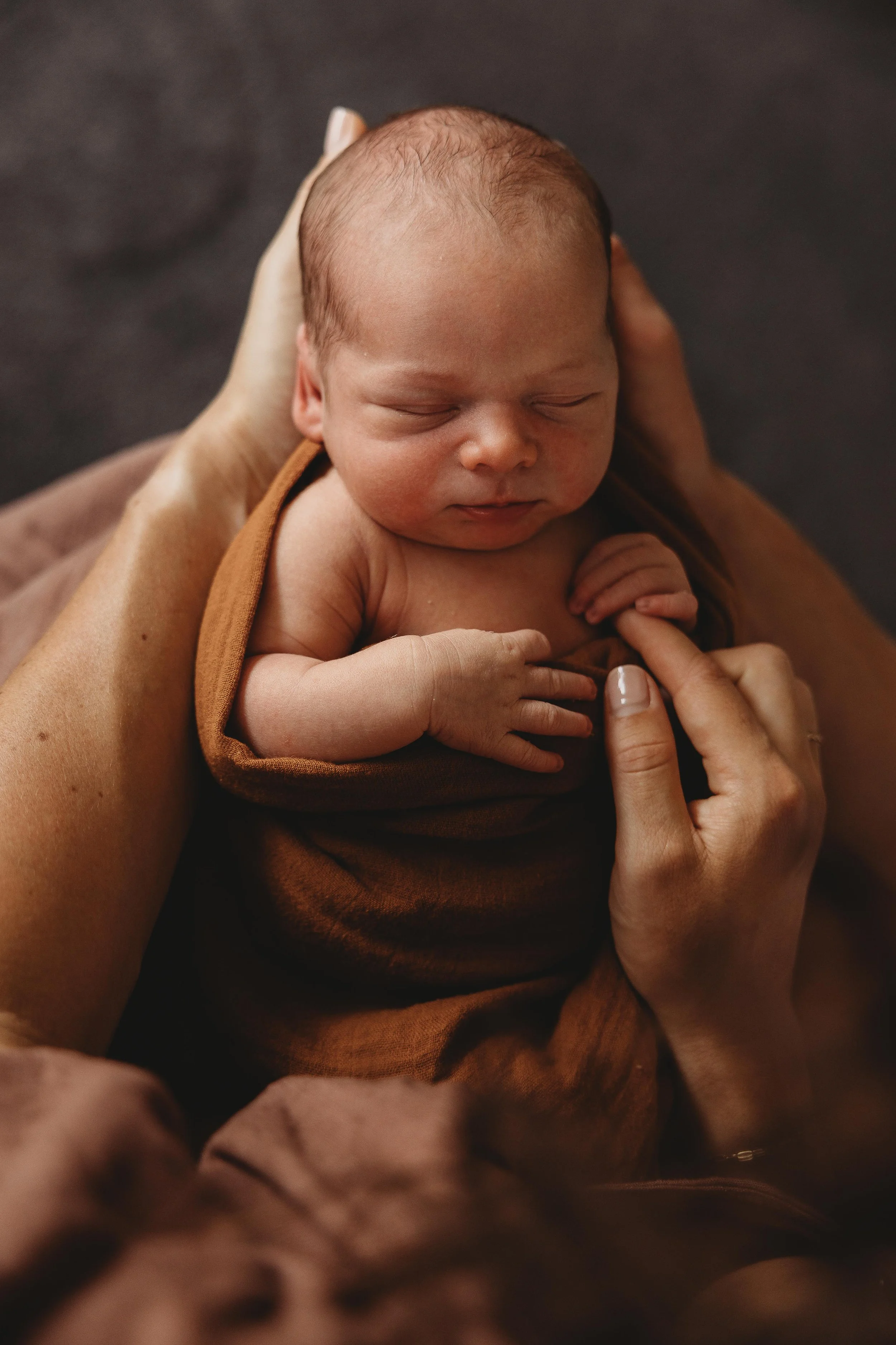 Newborn baby being held holding on mums finger