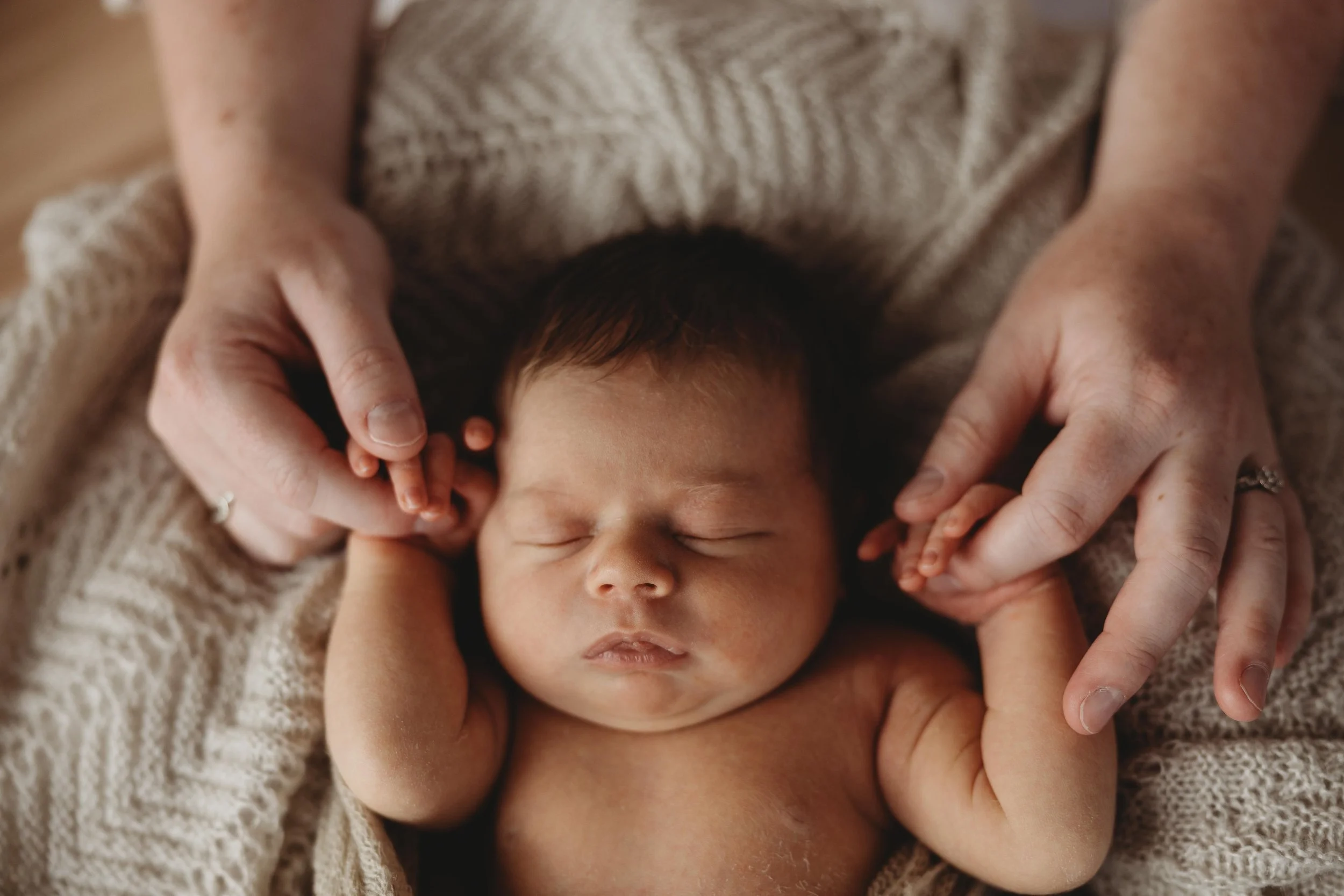 newborn baby holding hands with mum