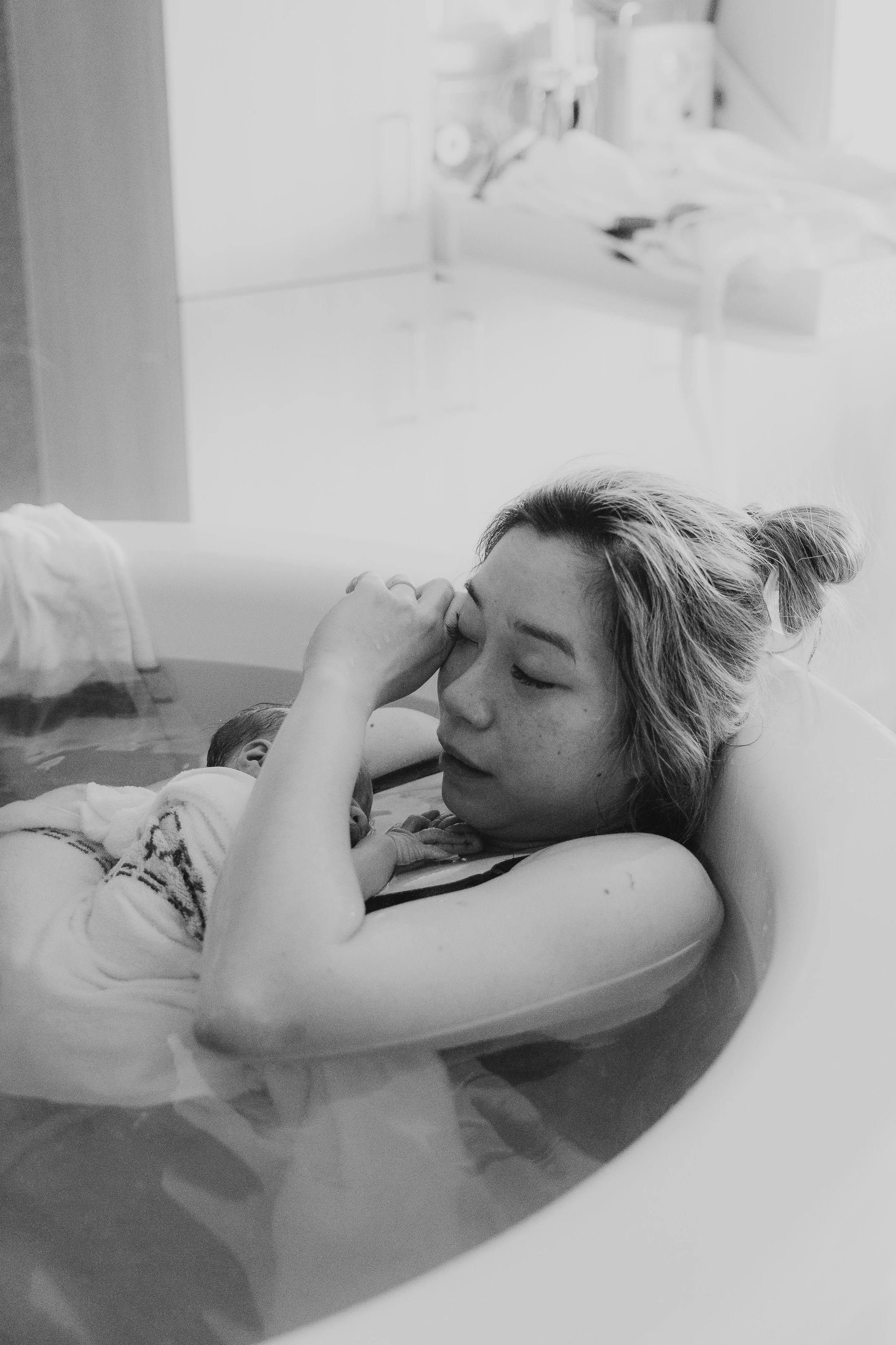 mother in birthing tub holding new baby