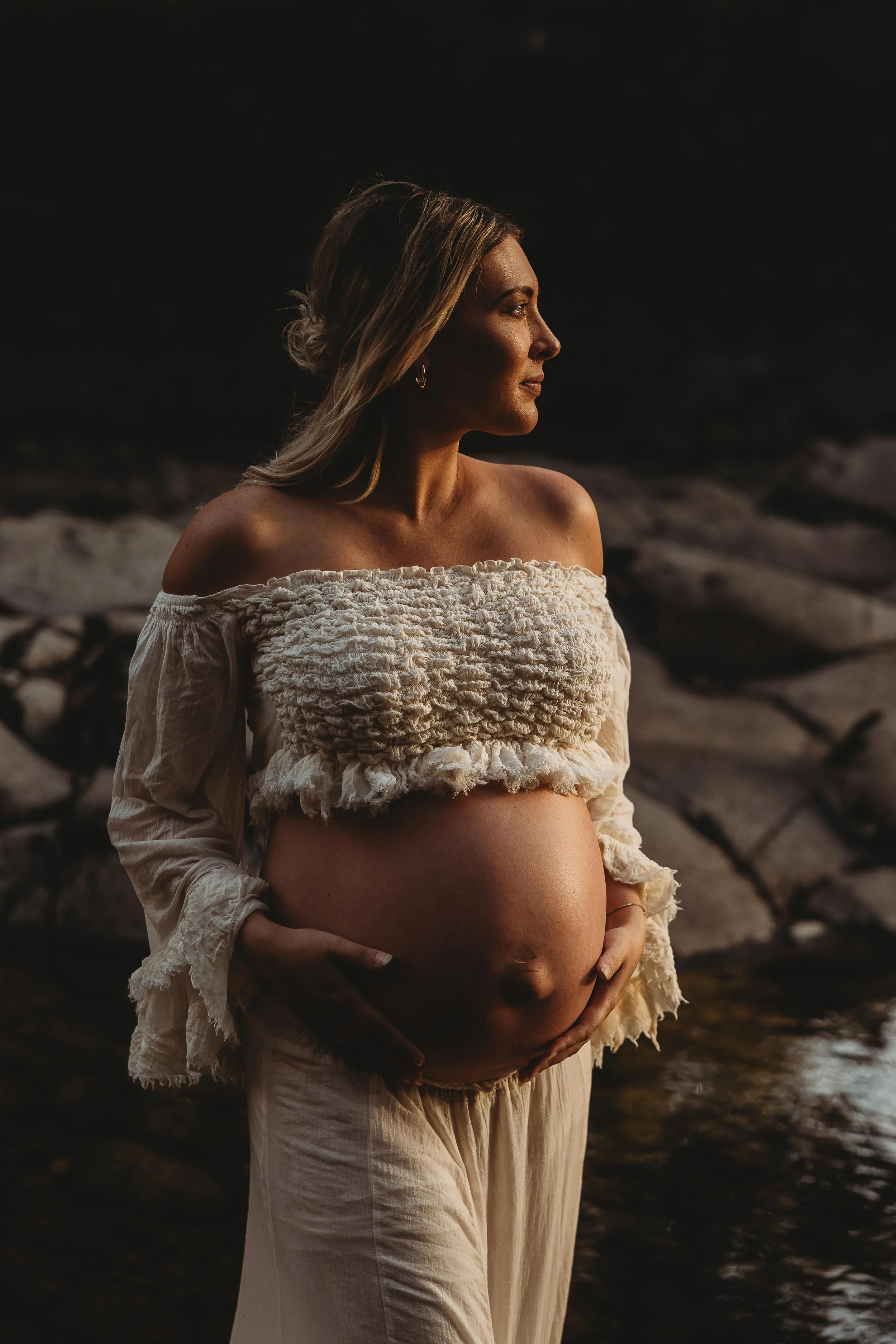 Pregnant mum holding her baby belly in golden light