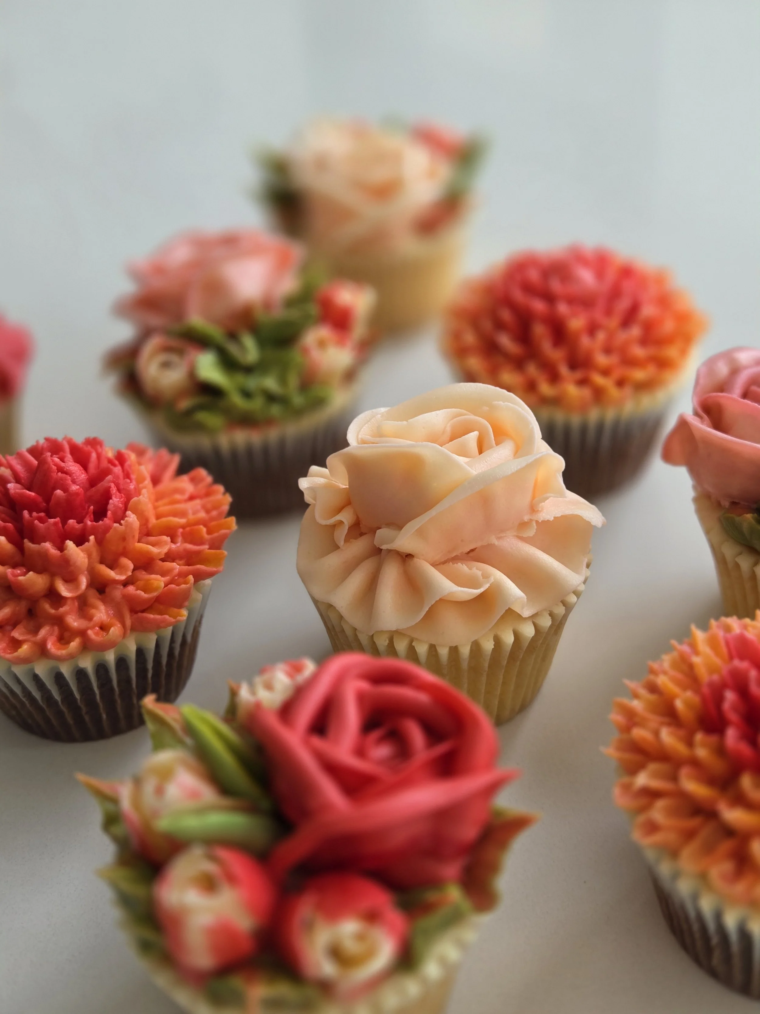 Various decorated cupcakes with colorful frosting and floral designs.