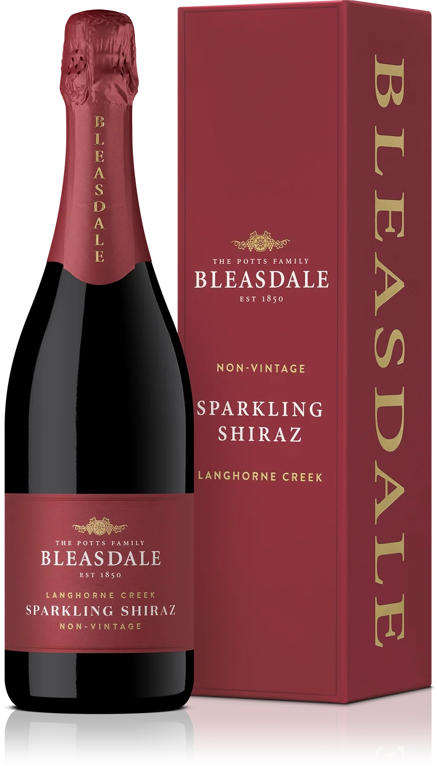 A bottle of Bleasdale sparkling Shiraz wine next to its red box packaging. The bottle has a red foil capsule and a label that matches the box, indicating it is a non-vintage, Langhorne Creek, Sparkling Shiraz from Bleasdale, established in 1850.