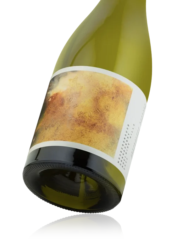 A tilted wine bottle with an abstract colorful label, lying on a reflective surface.
