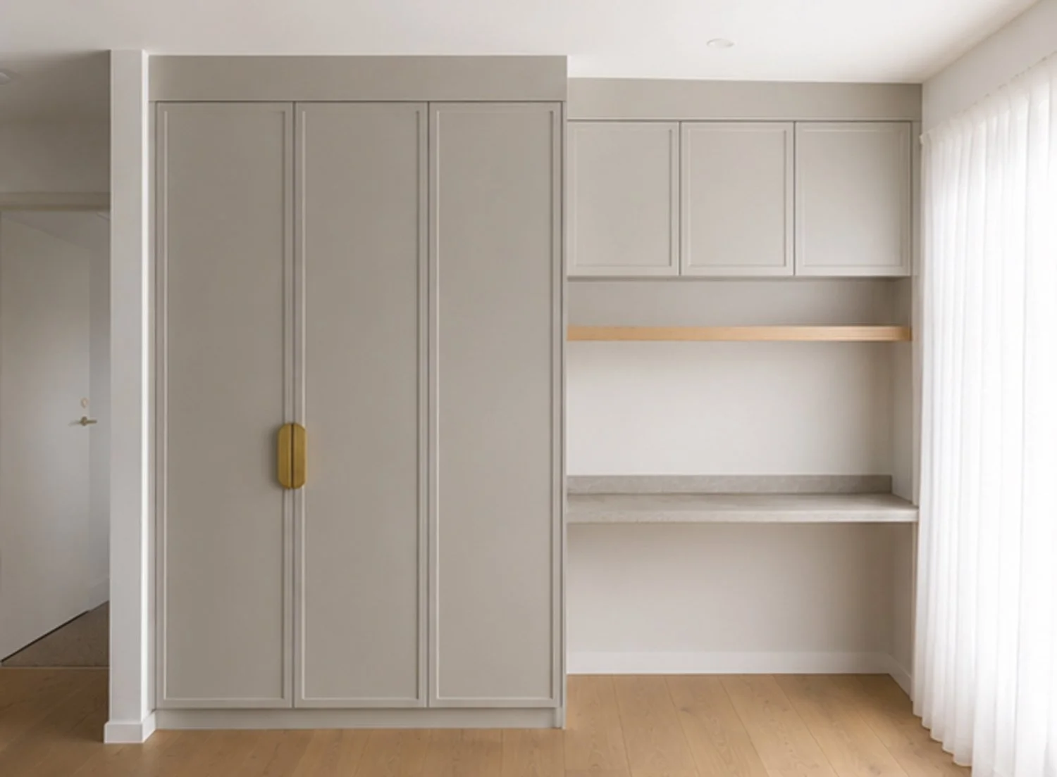 Built-in study area with stone desktop, shelving and cupboard with gold handle finishes.