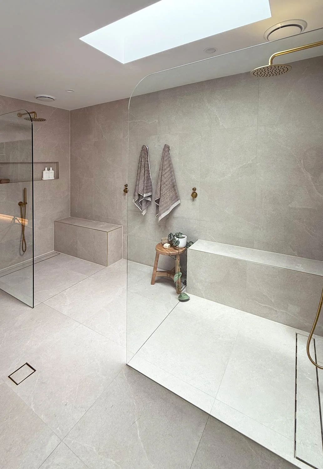 Large double walk-in shower with grey tiles, gold tapware and skylight above, designed by Christine Fletcher Design, Queensland interior designer.