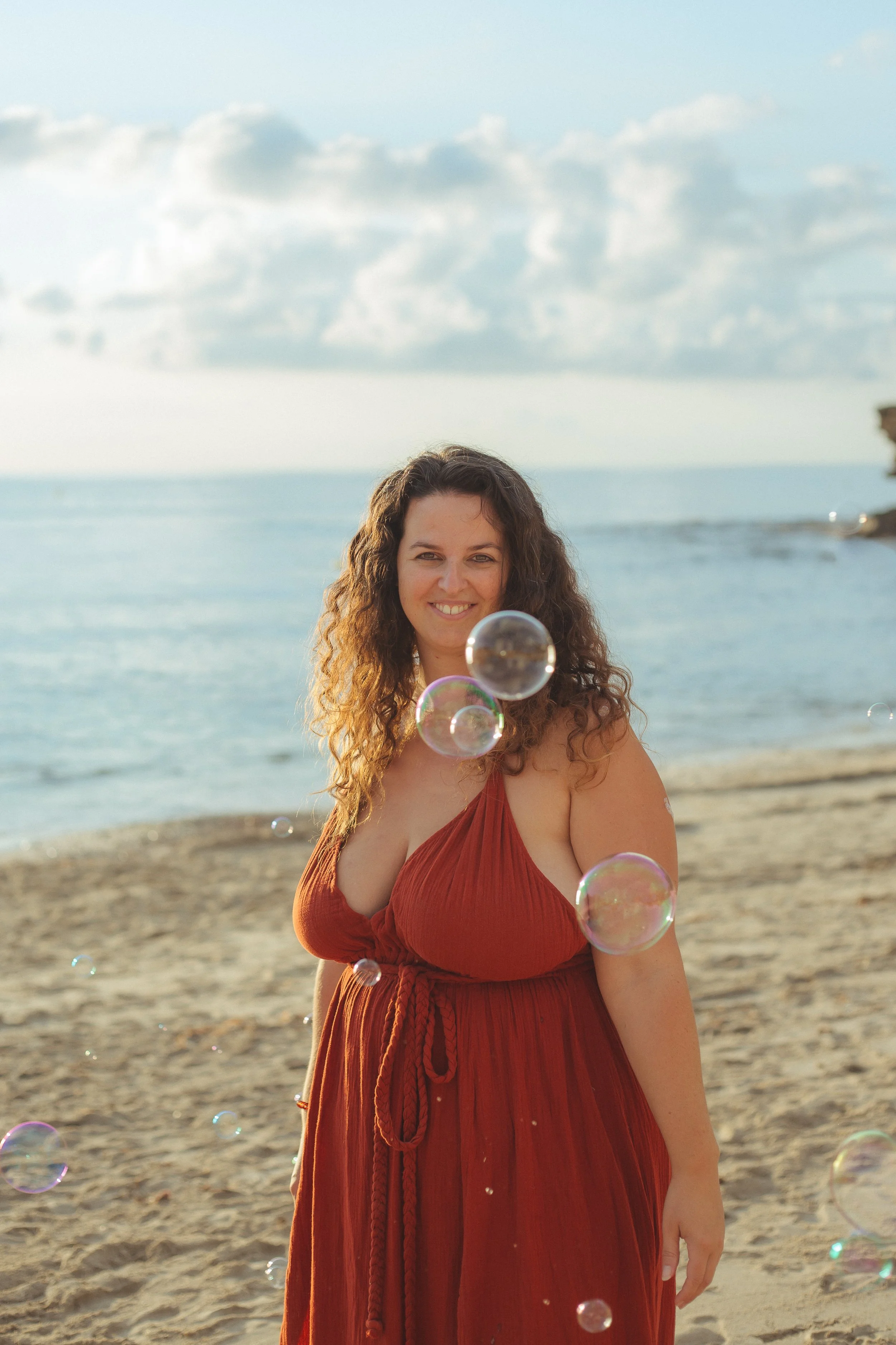 Maartje Wammes on the beach in a rust-colored dress, surrounded by bubbles  follow on Instagram
