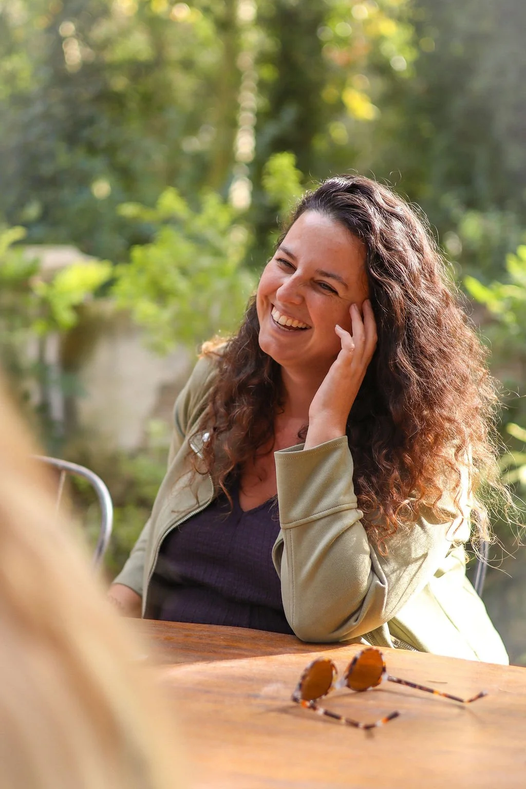 Maartje Wammes smiling outdoors at a wooden table — what she naturally does is zoom out and find the pattern