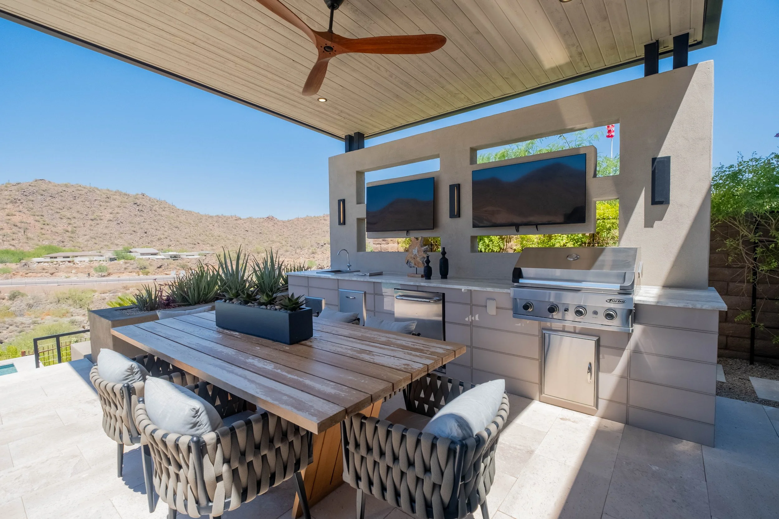 Outdoor patio with dining area, ceiling fan, built-in grill, and mountain view.