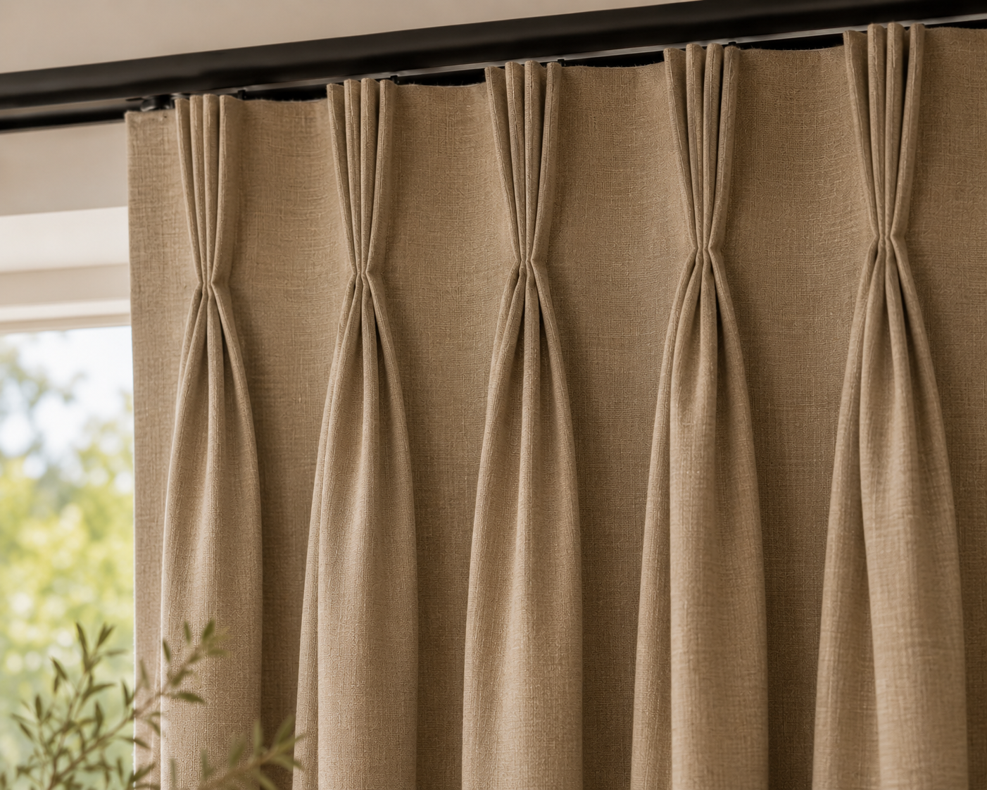 Beige curtains hanging from a black curtain rod with a view of trees outside in the background.
