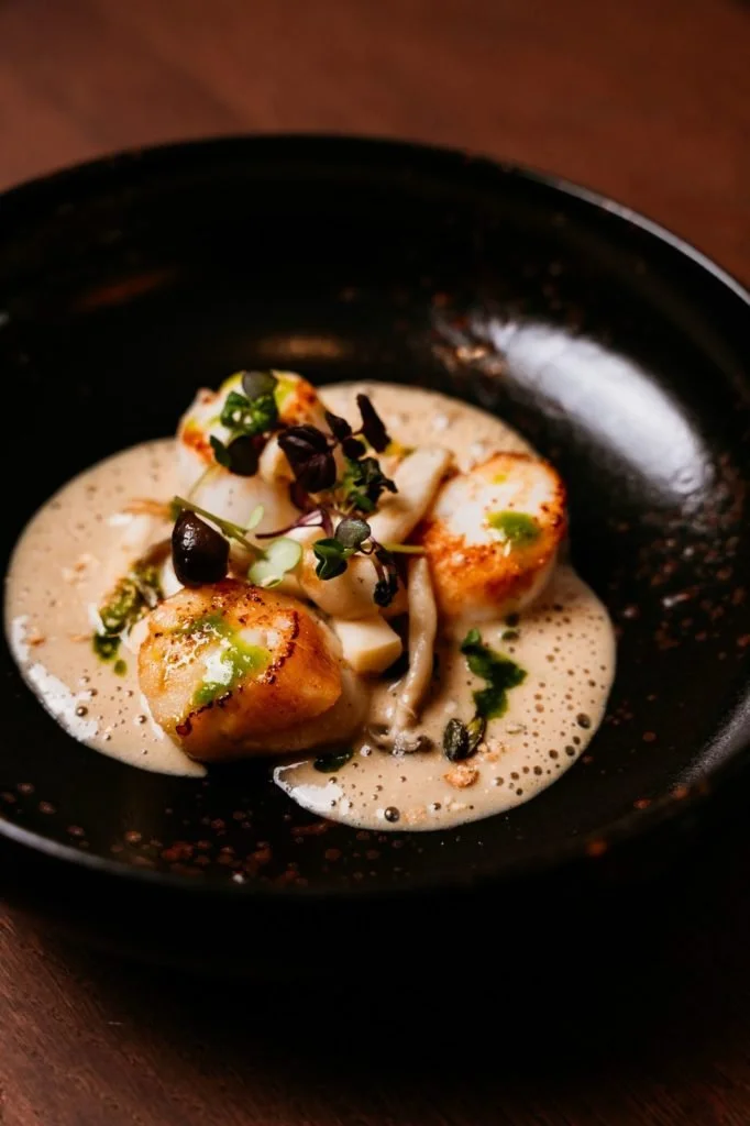 Palet de fruits de mer avec une sauce crémeuse, garniture de microgreens, et champignons