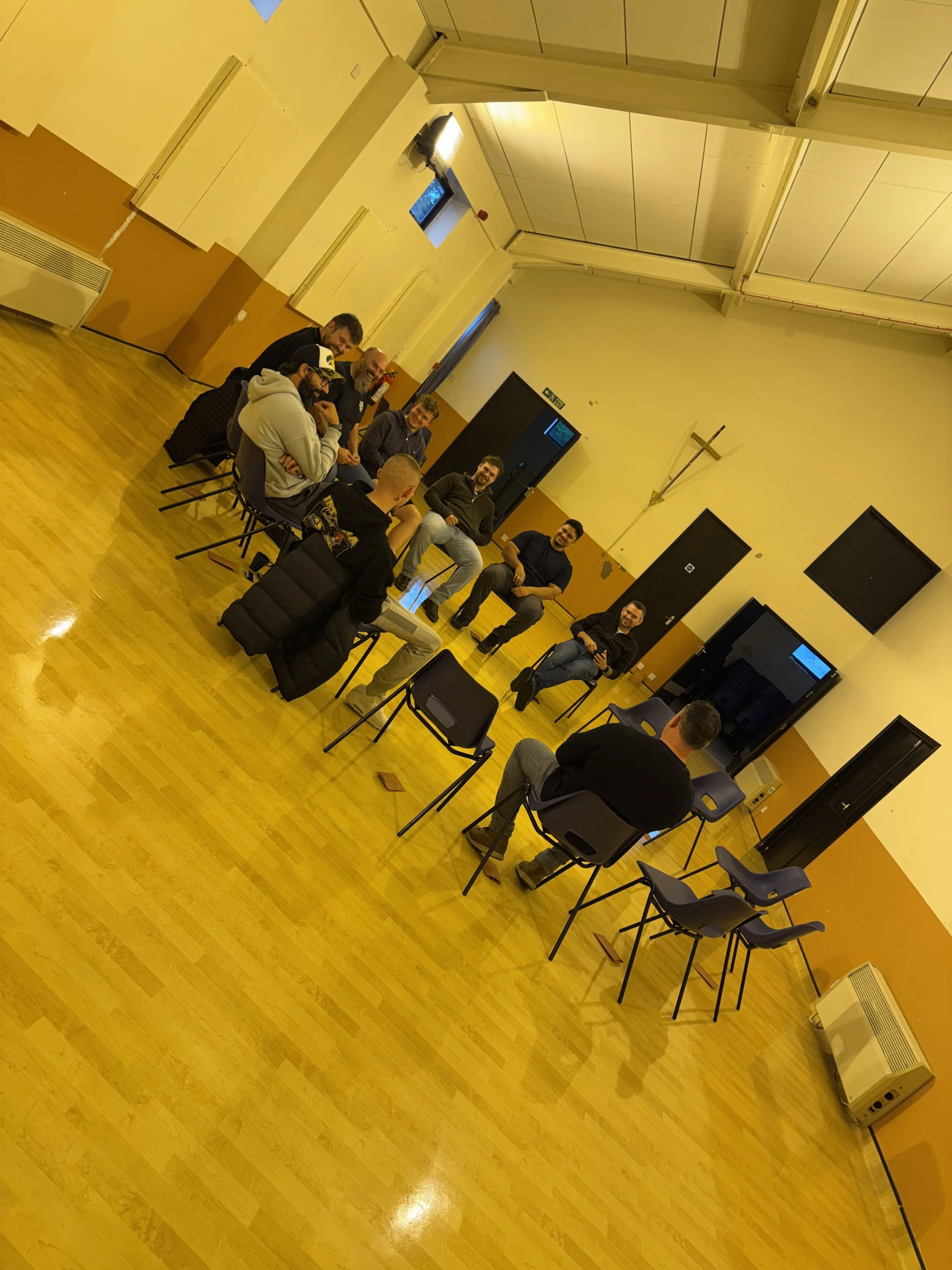 a group of men sitting in a circle. support. therapy. trauma. depression. suicide. suicidal. sad. positive. help. community. brotherhood. hold the line projects. mentoring. coaching. talking therapy. talk.