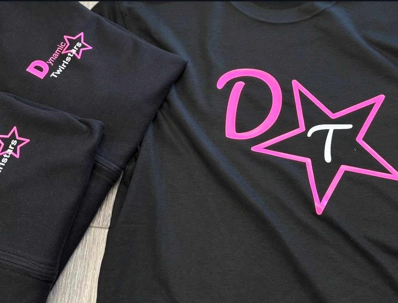 Black t-shirts with pink and white logo that reads 'Dynamic Twisters' inside a pink-outlined star, with the letter 'D' and a large pink star with a white 'T' inside.