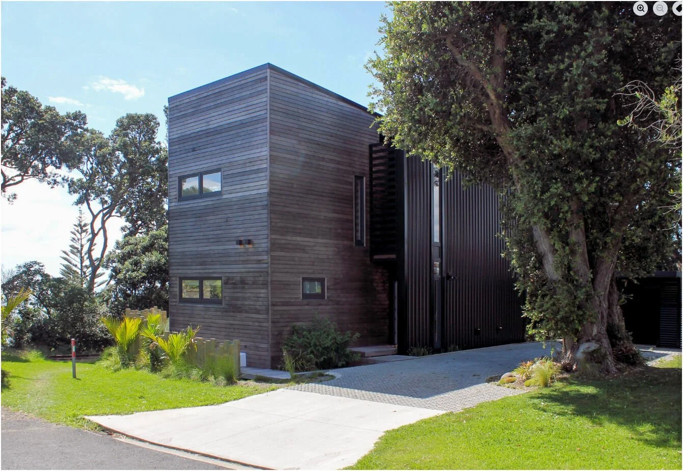 Adams Building architectural home with timber and dark cladding surrounded by established trees in Fitzroy, New Plymouth.
