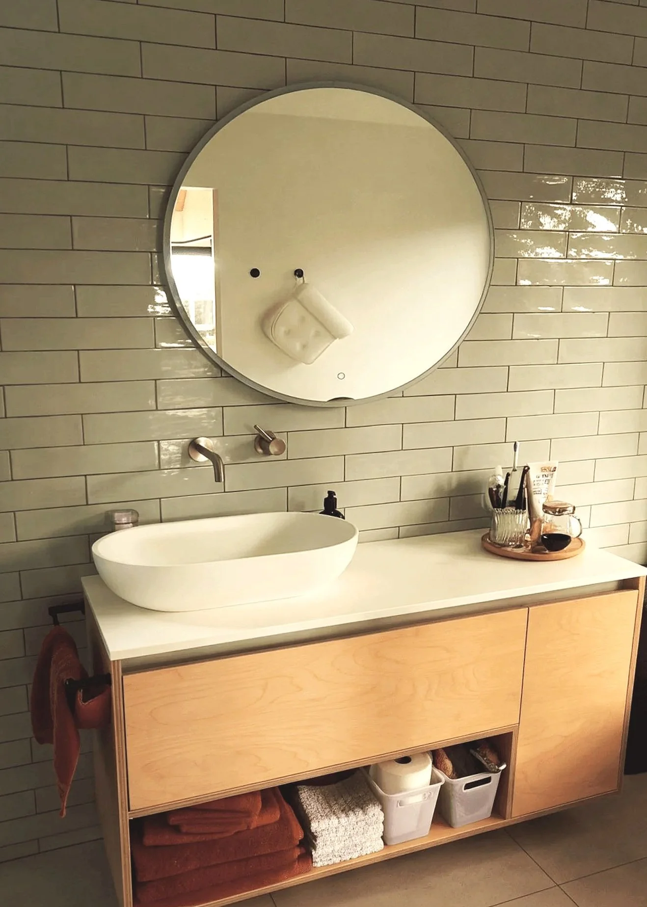 Adams Building modern bathroom vanity with timber cabinetry, round mirror and tiled feature wall in Fitzroy, New Plymouth.