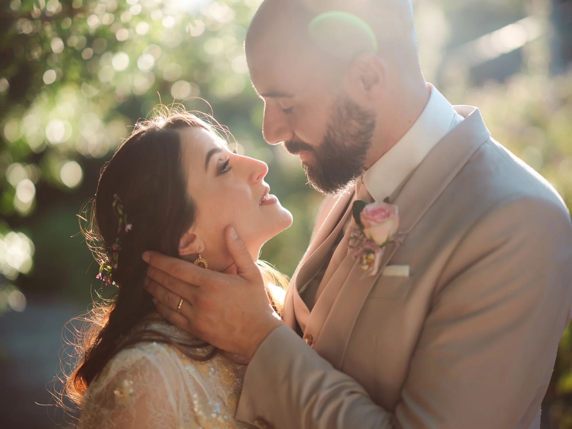 Sposo che tiene delicatamente il volto della sposa mentre lei lo guarda intensamente negli occhi