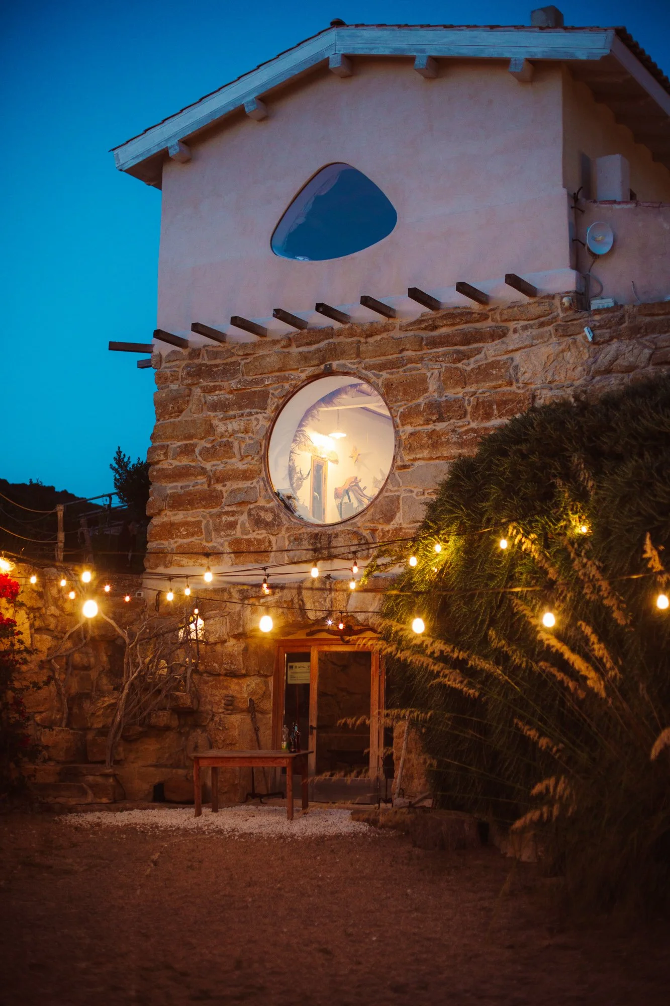 Struttura in pietra di una location per matrimoni in Sardegna illuminata da lucine catenaria al crepuscolo