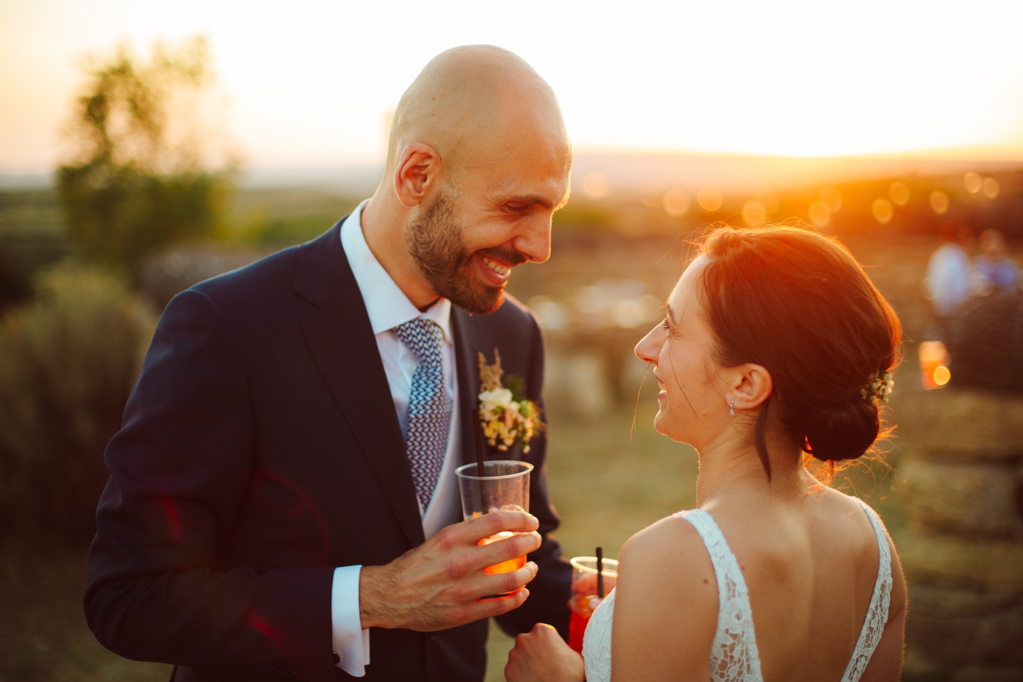 Gli sposi si guardano sorridenti con un cocktail in mano durante l'aperitivo di nozze