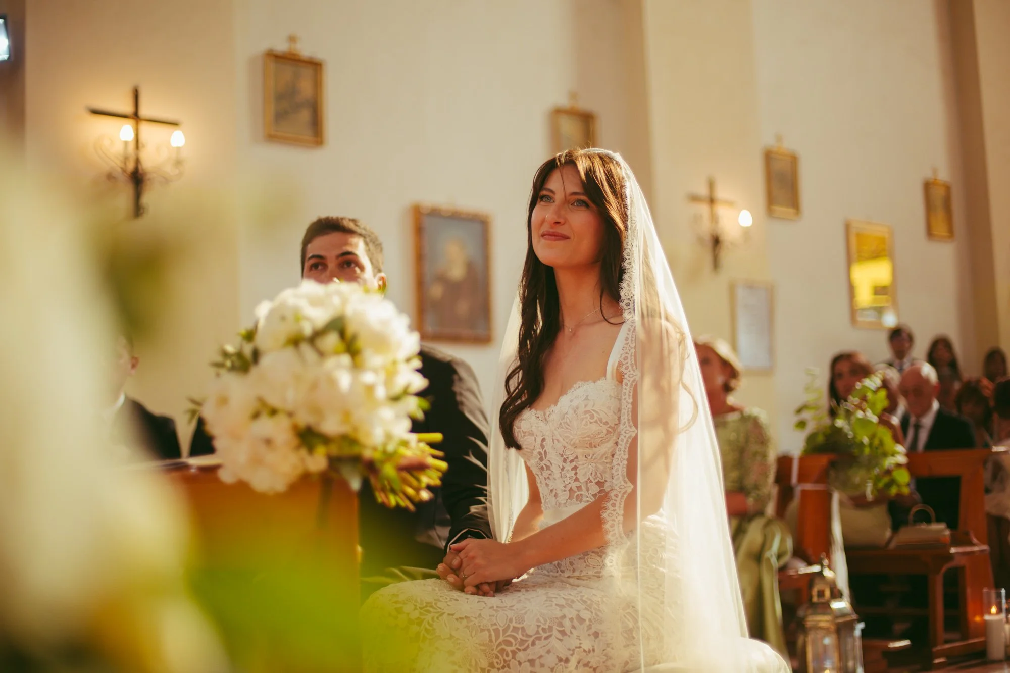 La sposa sorride con emozione seduta all'altare durante la celebrazione delle nozze in chiesa