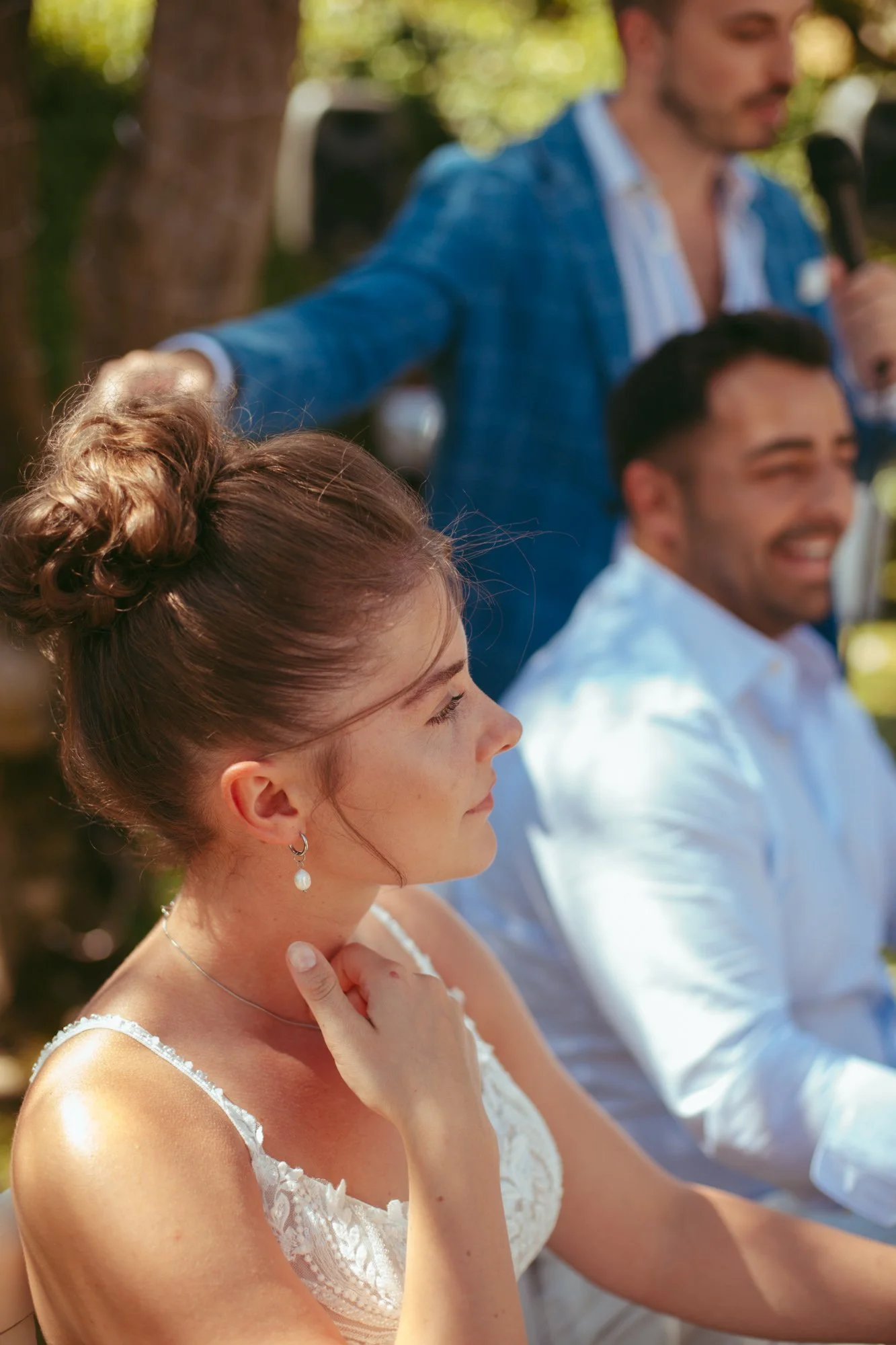 Primo piano di profilo della sposa che ascolta emozionata il discorso di un invitato al microfono