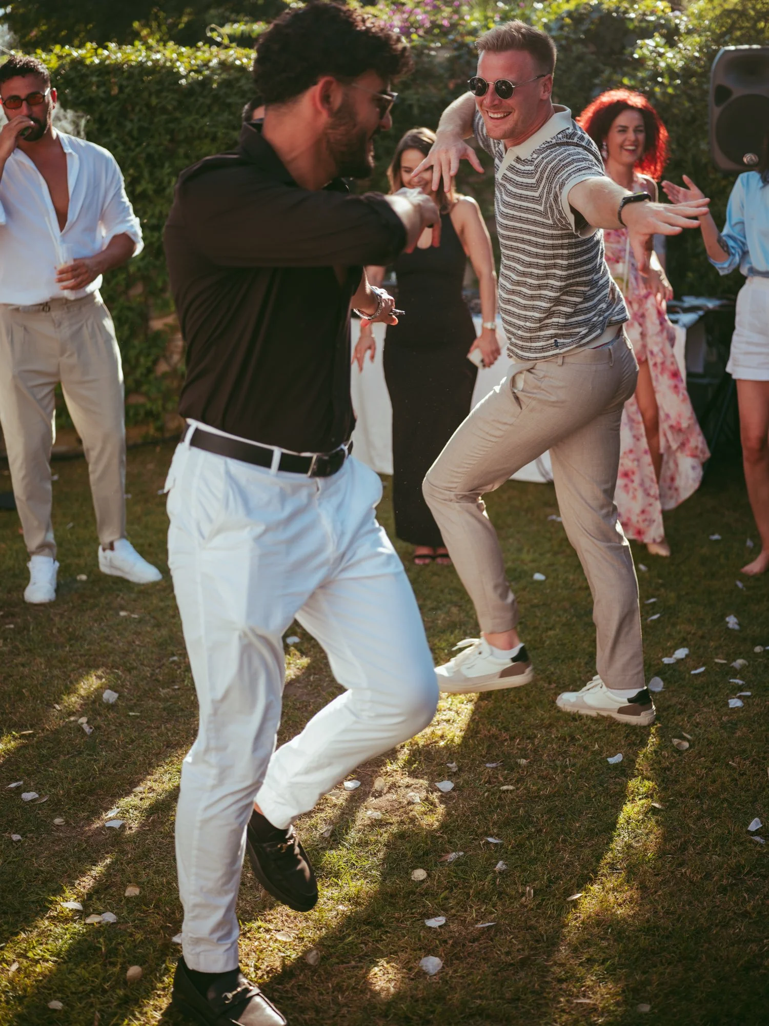 Due amici e invitati al matrimonio accennano passi di danza divertenti sul prato durante la festa