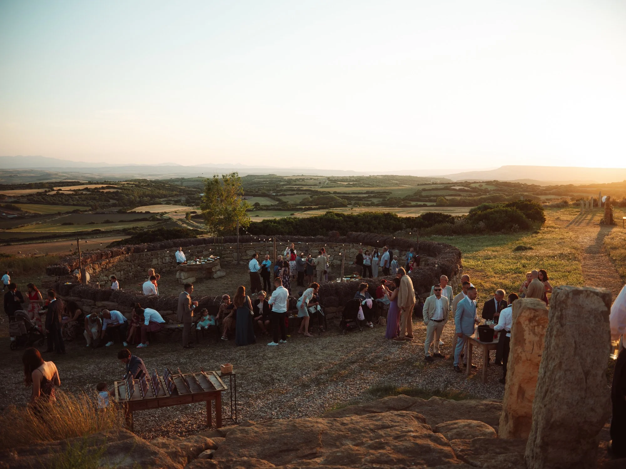 Aperitivo di matrimonio all'aperto al tramonto con vista panoramica sulle colline sarde e ospiti nell'area ricevimento