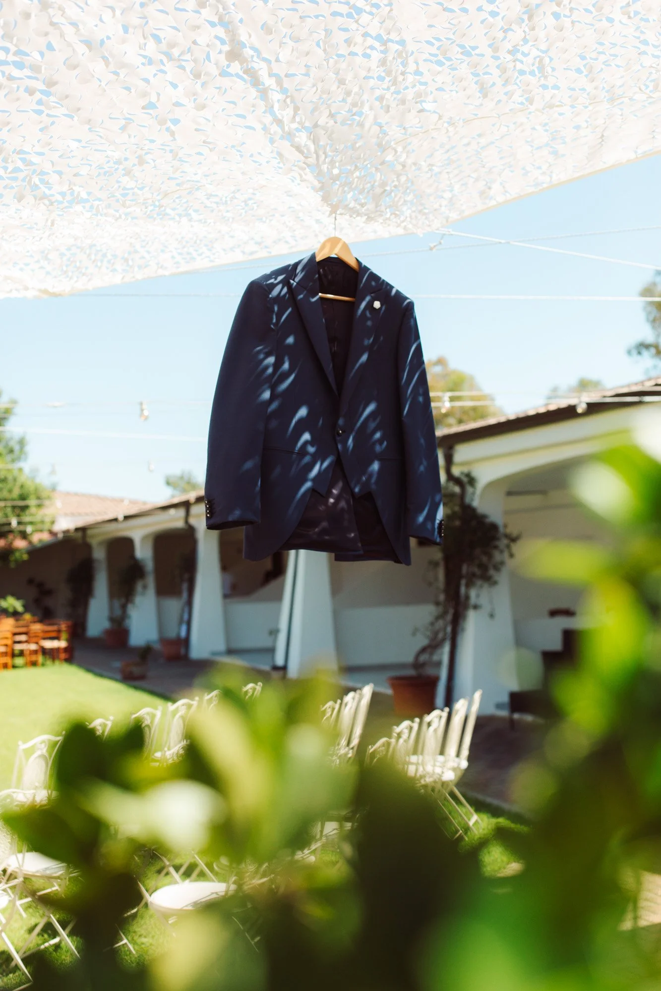 Elegante abito da sposo blu sartoriale appeso all'aperto nel giardino della location di nozze.