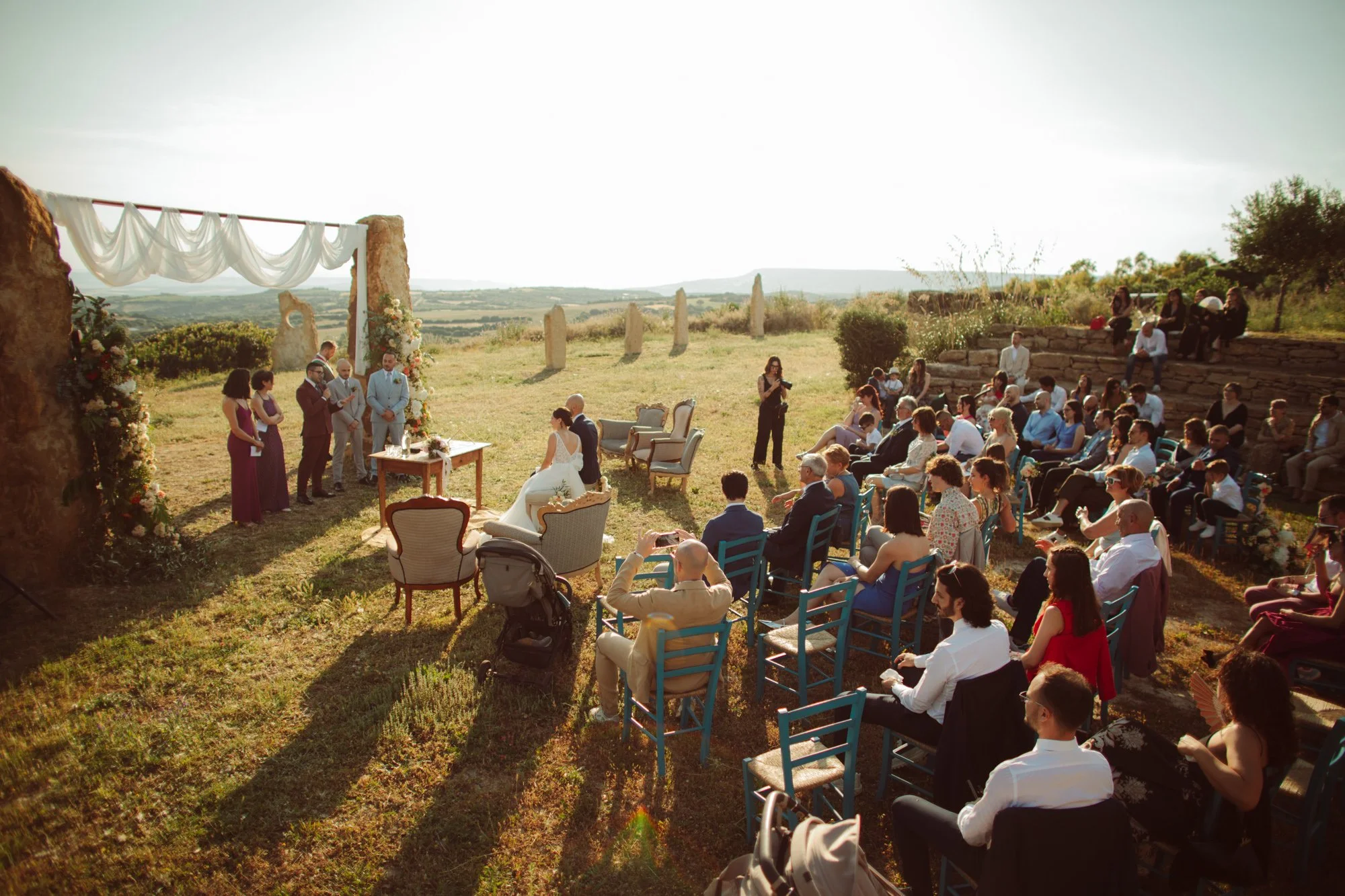 Cerimonia di matrimonio all'aperto al tramonto con ospiti e vista panoramica in Sardegna