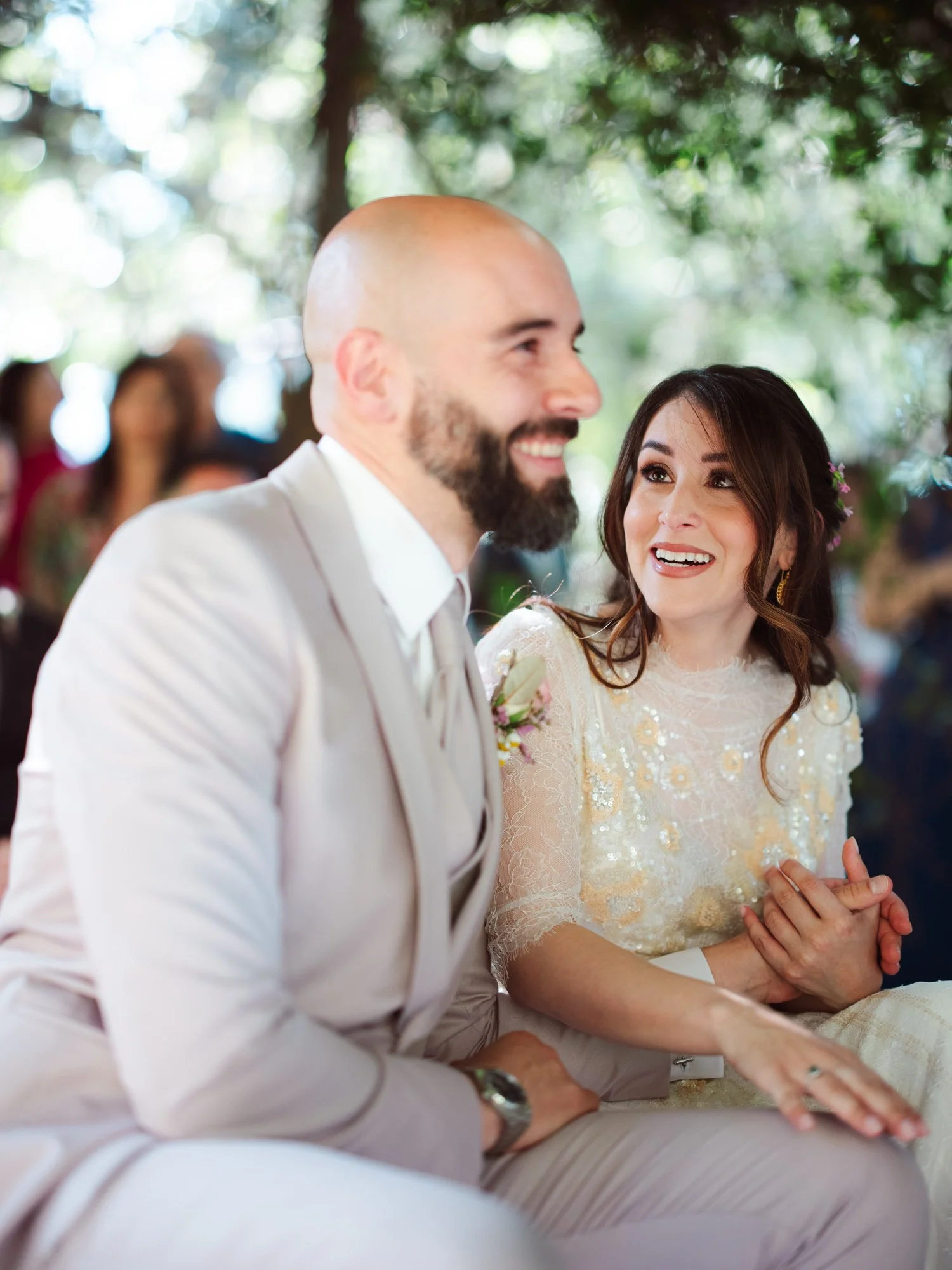 La sposa guarda con sguardo pieno d'amore e sorriso felice lo sposo seduto accanto a lei durante la cerimonia