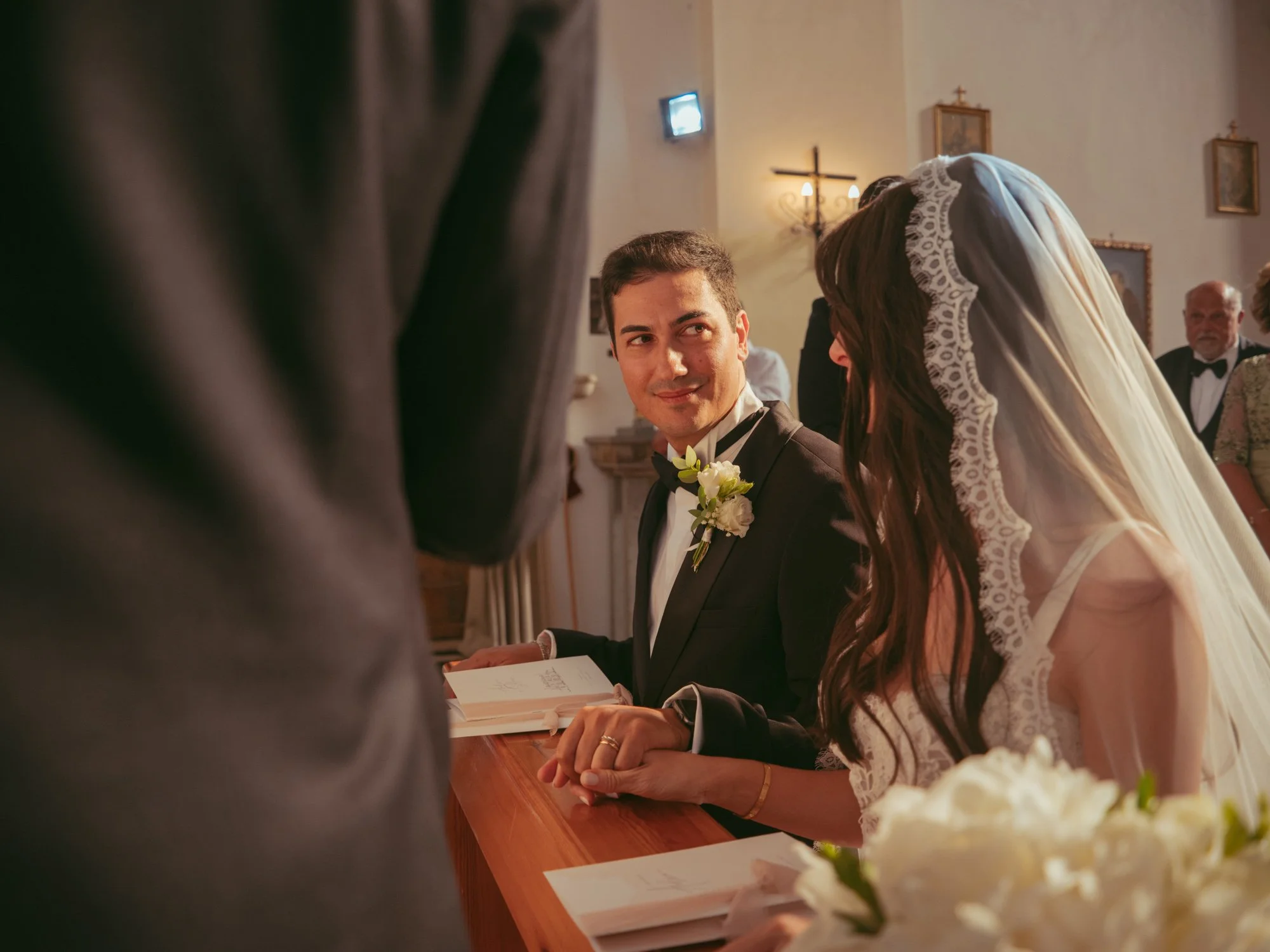 Lo sposo guarda la sposa con complicità ed emozione durante il rito del matrimonio in chiesa