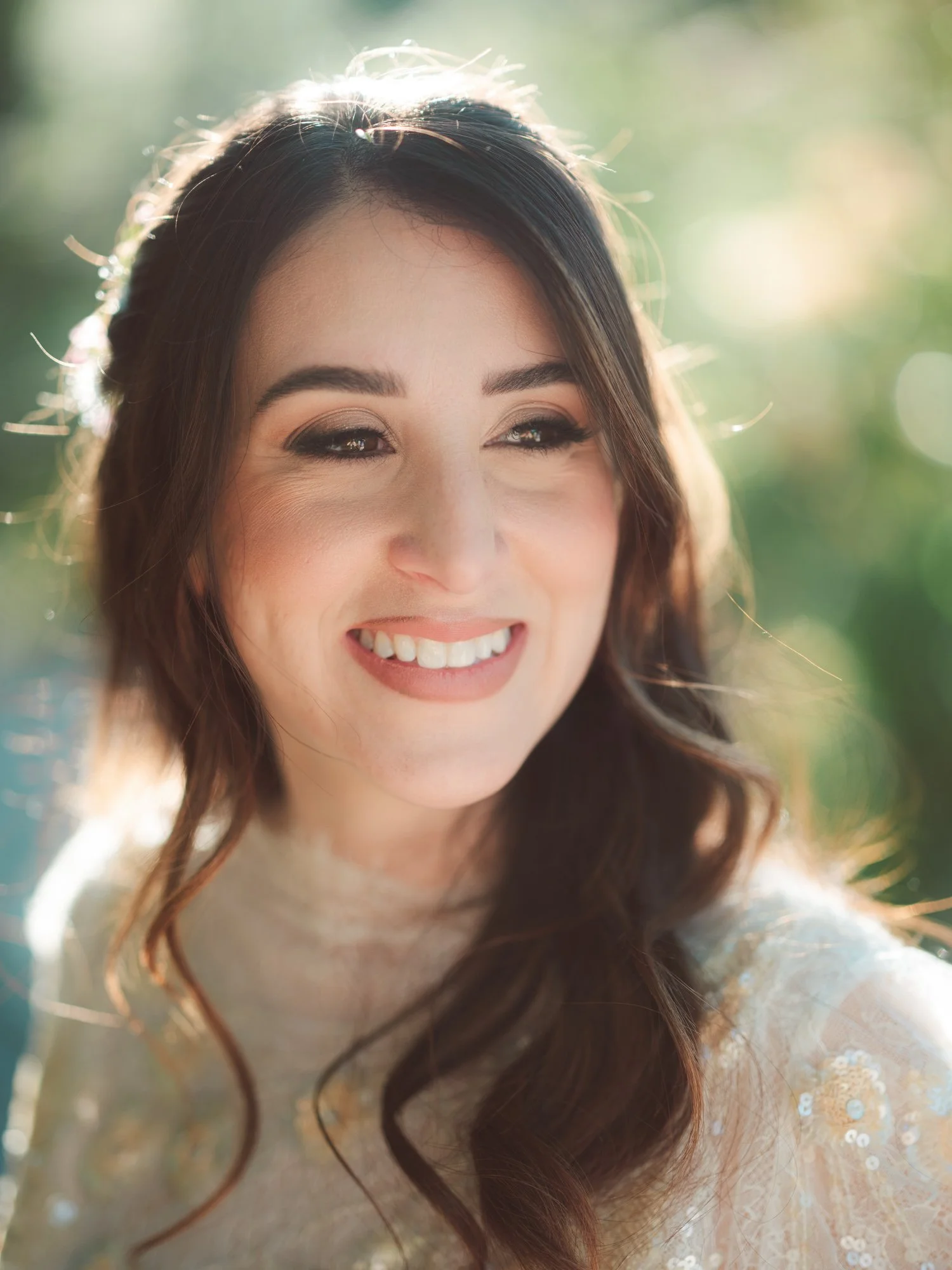 Primo piano stretto e luminoso della sposa che sorride felice con trucco naturale ed acconciatura semi-raccolta