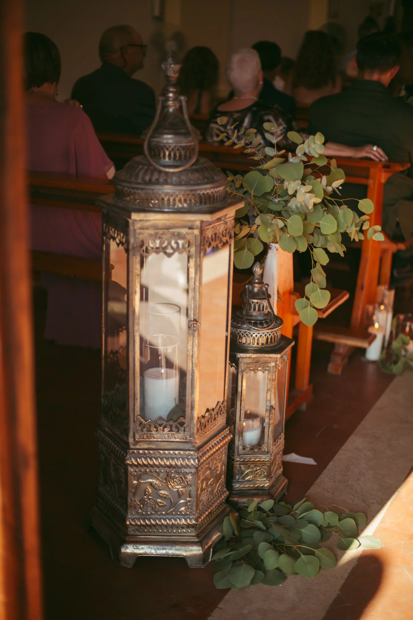 Lanterne vintage in metallo lavorato e candele posizionate lungo la navata della chiesa come allestimento nuziale