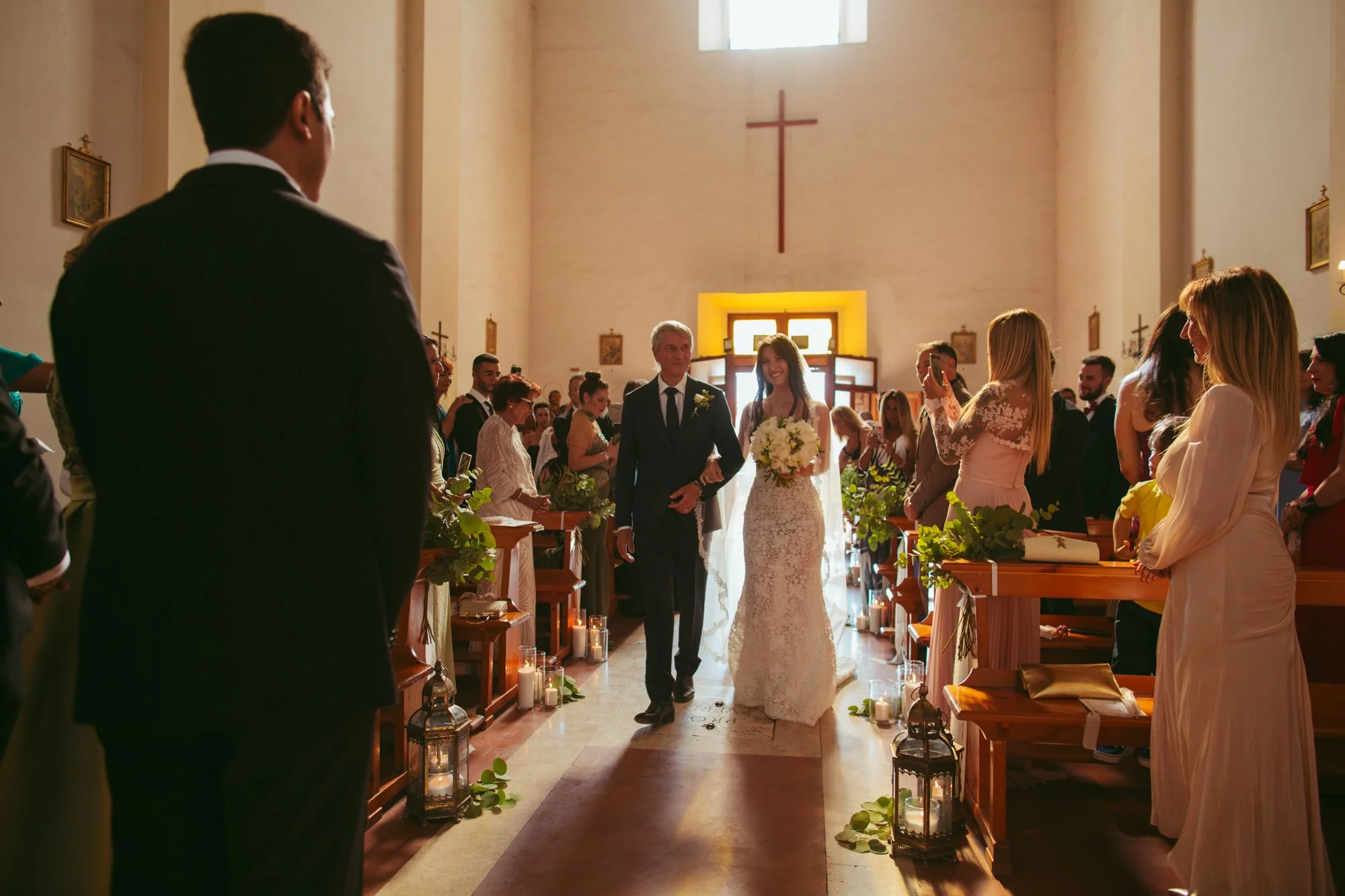 La sposa entra in chiesa al braccio del padre mentre lo sposo la attende all'altare a Borgo di Tragliata