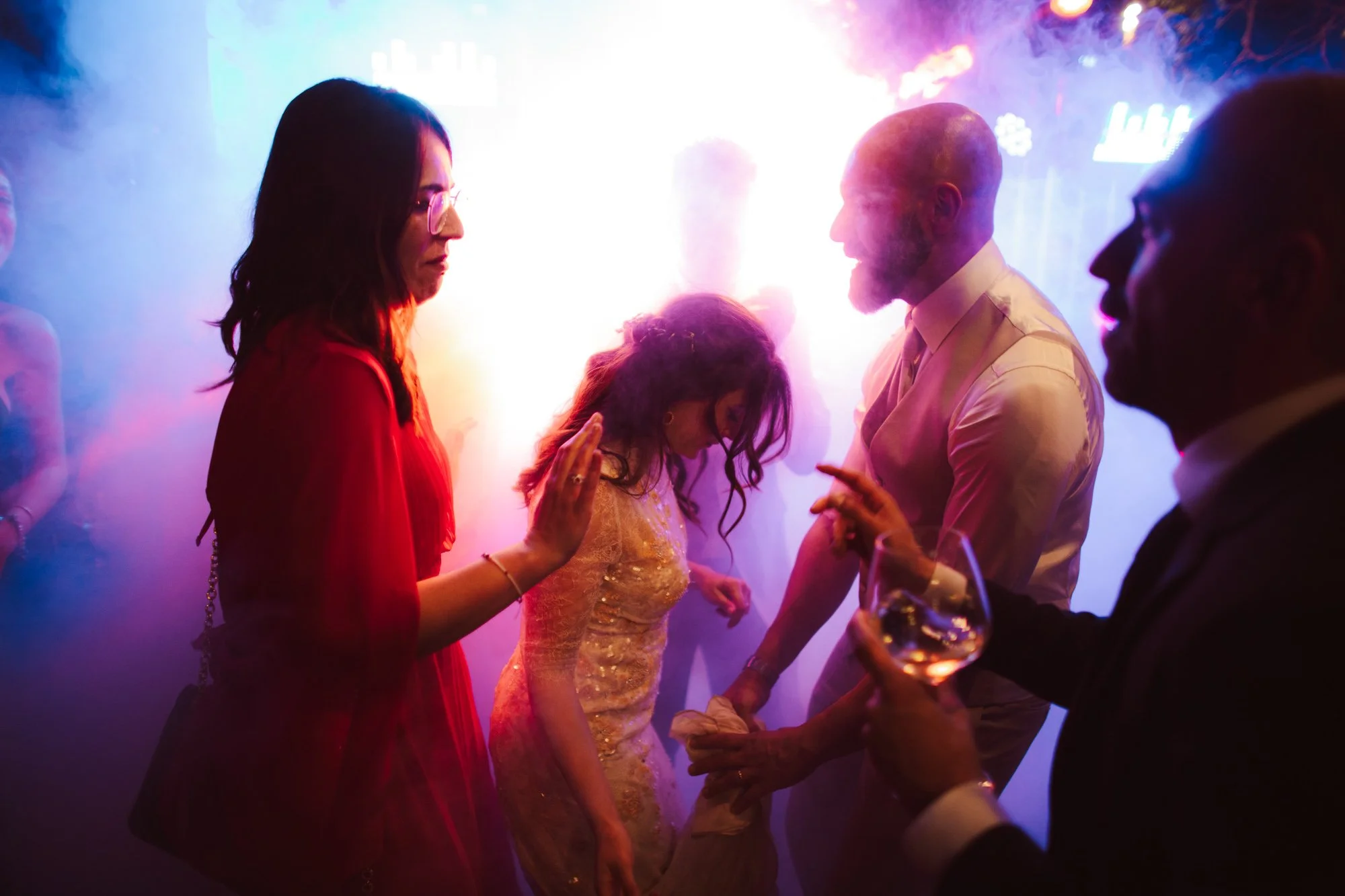 Sposa in abito dorato ed invitati ballano al centro della pista illuminati da vivaci luci led neon fucsia e blu