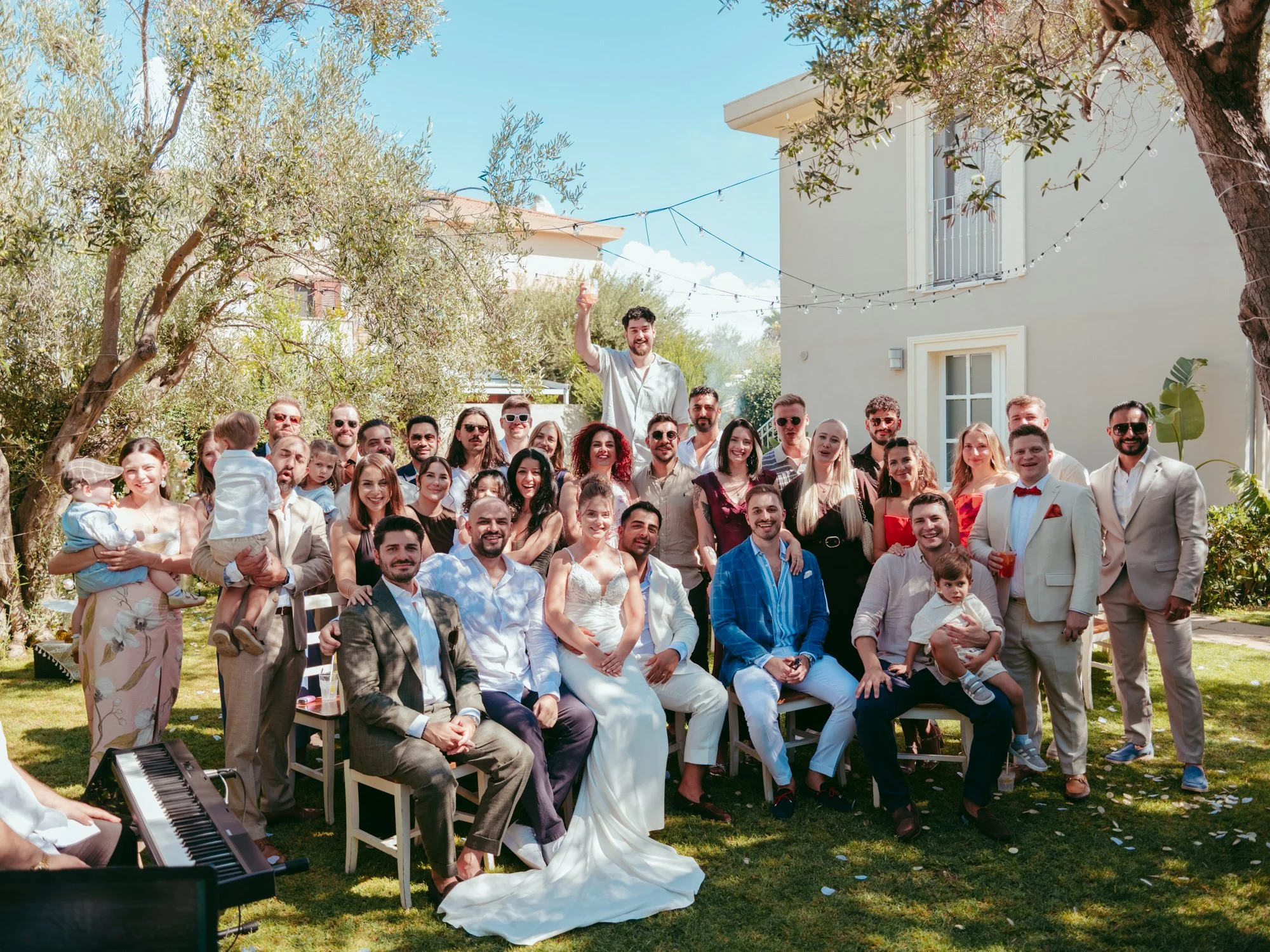 Grande foto di gruppo con gli sposi al centro circondati da tutti gli invitati nel giardino della villa