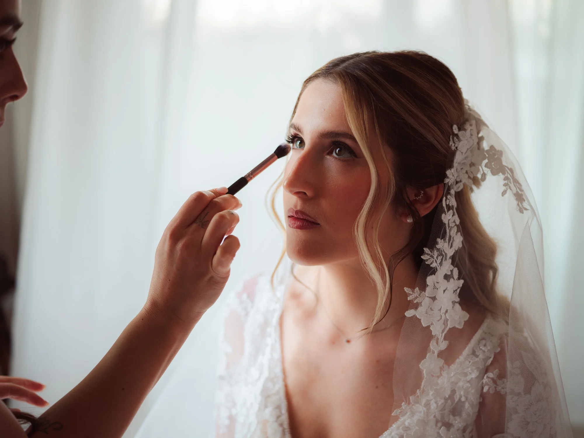 Primo piano della sposa durante l'applicazione dell'ombretto sugli occhi con un pennello da make-up
