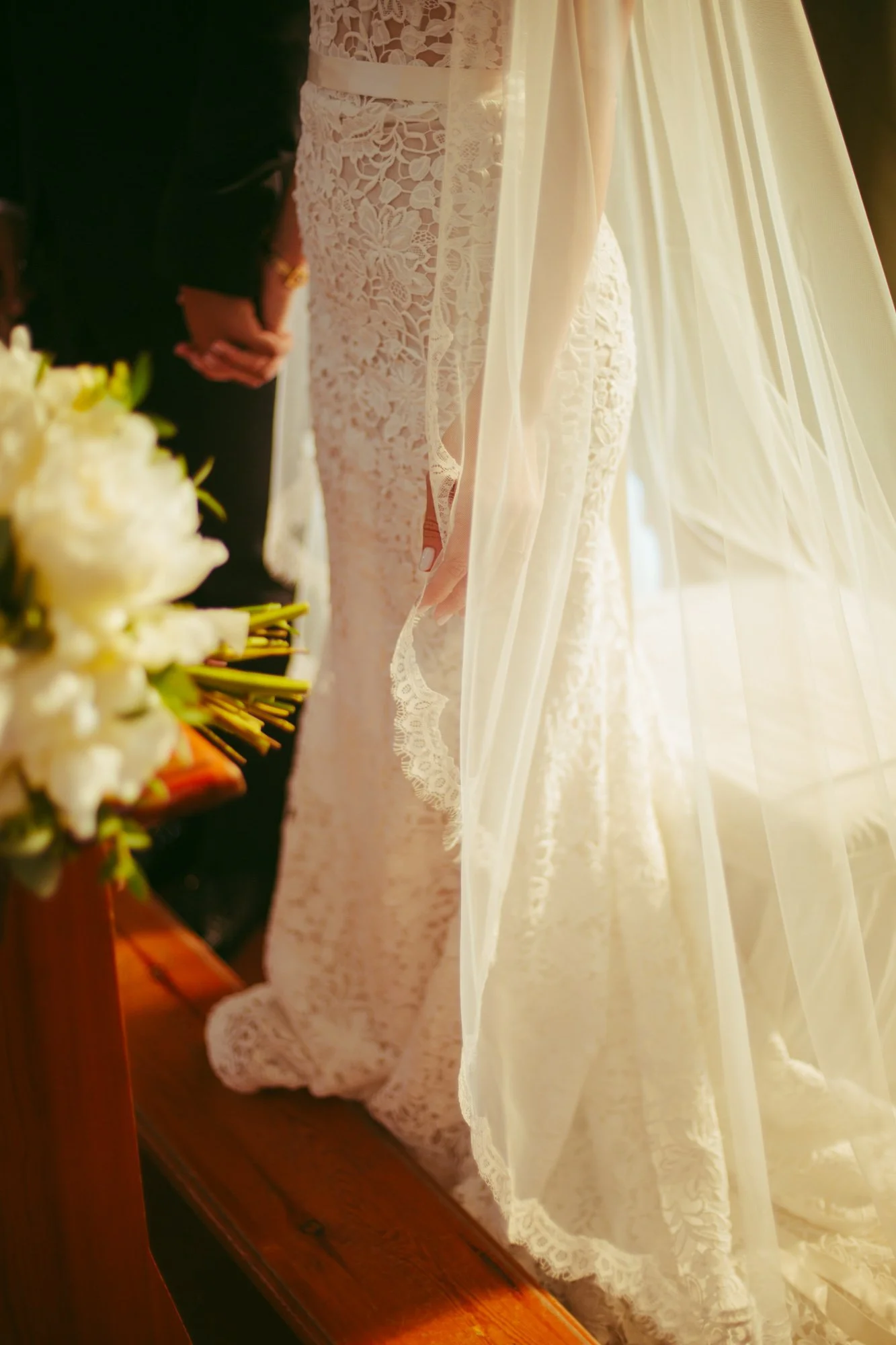 Dettaglio ravvicinato della trama in pizzo dell'abito da sposa e del velo elegante durante la cerimonia