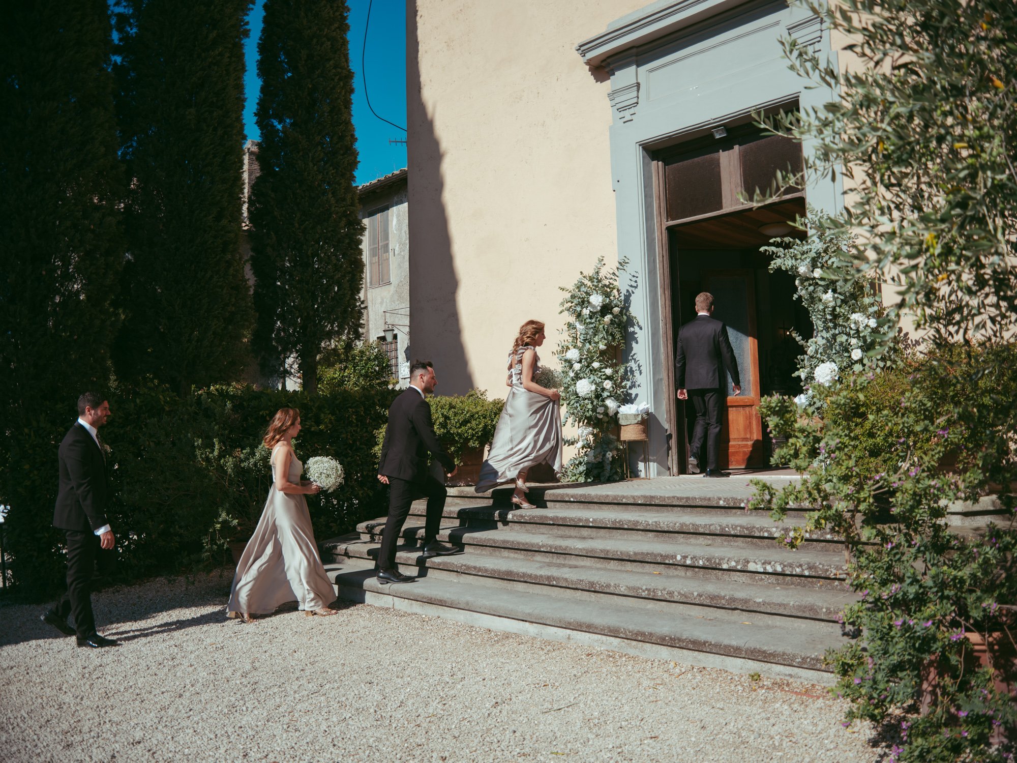 Gli invitati e le damigelle salgono la scalinata ed entrano nella chiesa addobbata con fiori bianchi