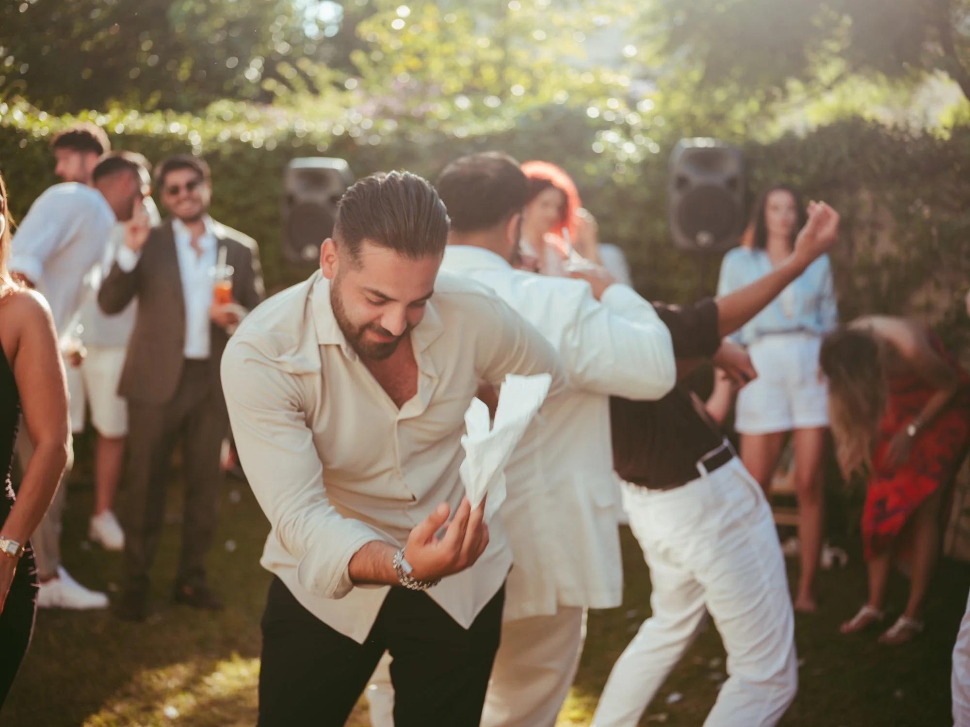 Invitato che si scatena ballando sul prato mentre sventola un tovagliolo bianco circondato dagli amici