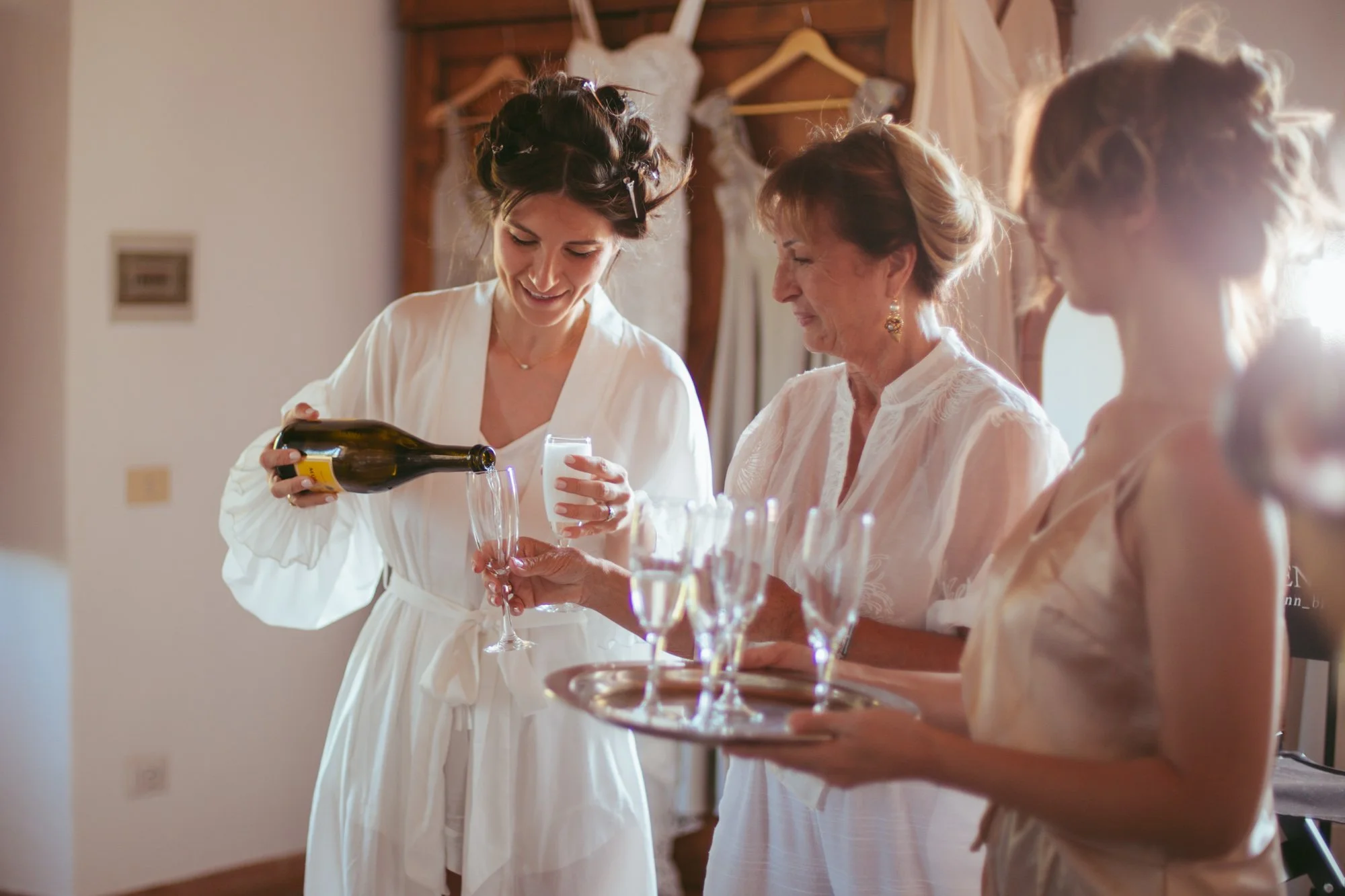 La sposa versa lo champagne per un brindisi con la madre e le amiche prima delle nozze