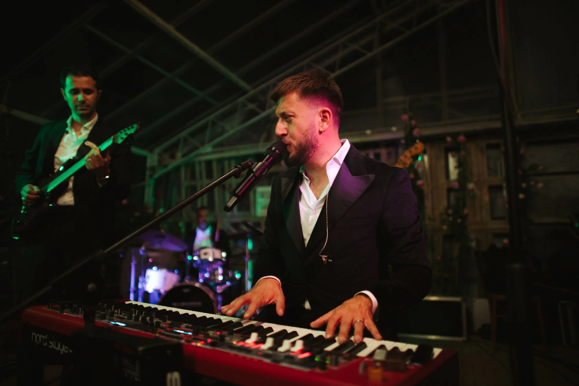 Un cantante e tastierista suona il piano e canta al microfono durante l'esibizione della live band