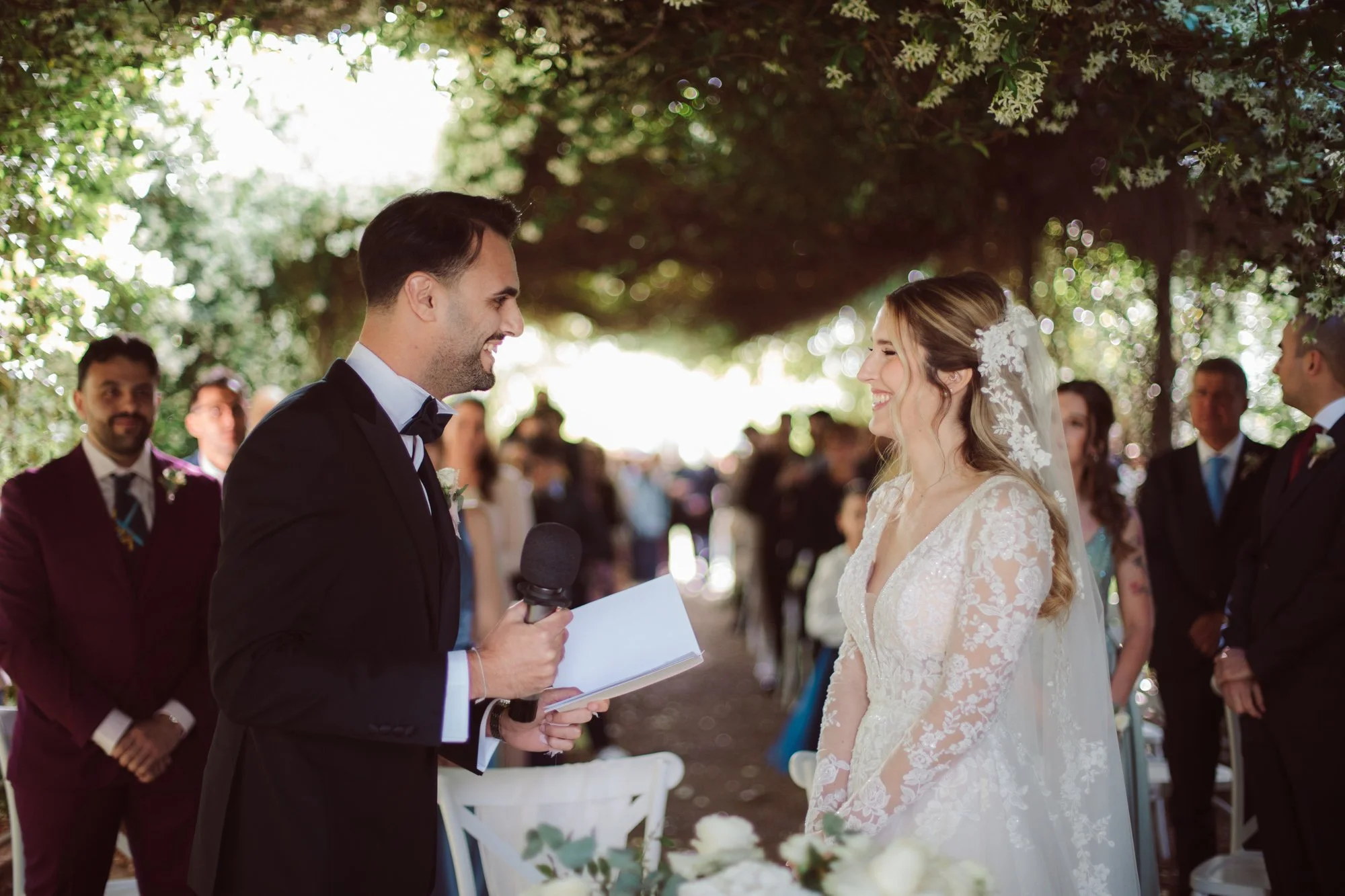 Lo sposo sorridente parla al microfono leggendo un foglio di promesse di fronte alla sposa durante la cerimonia