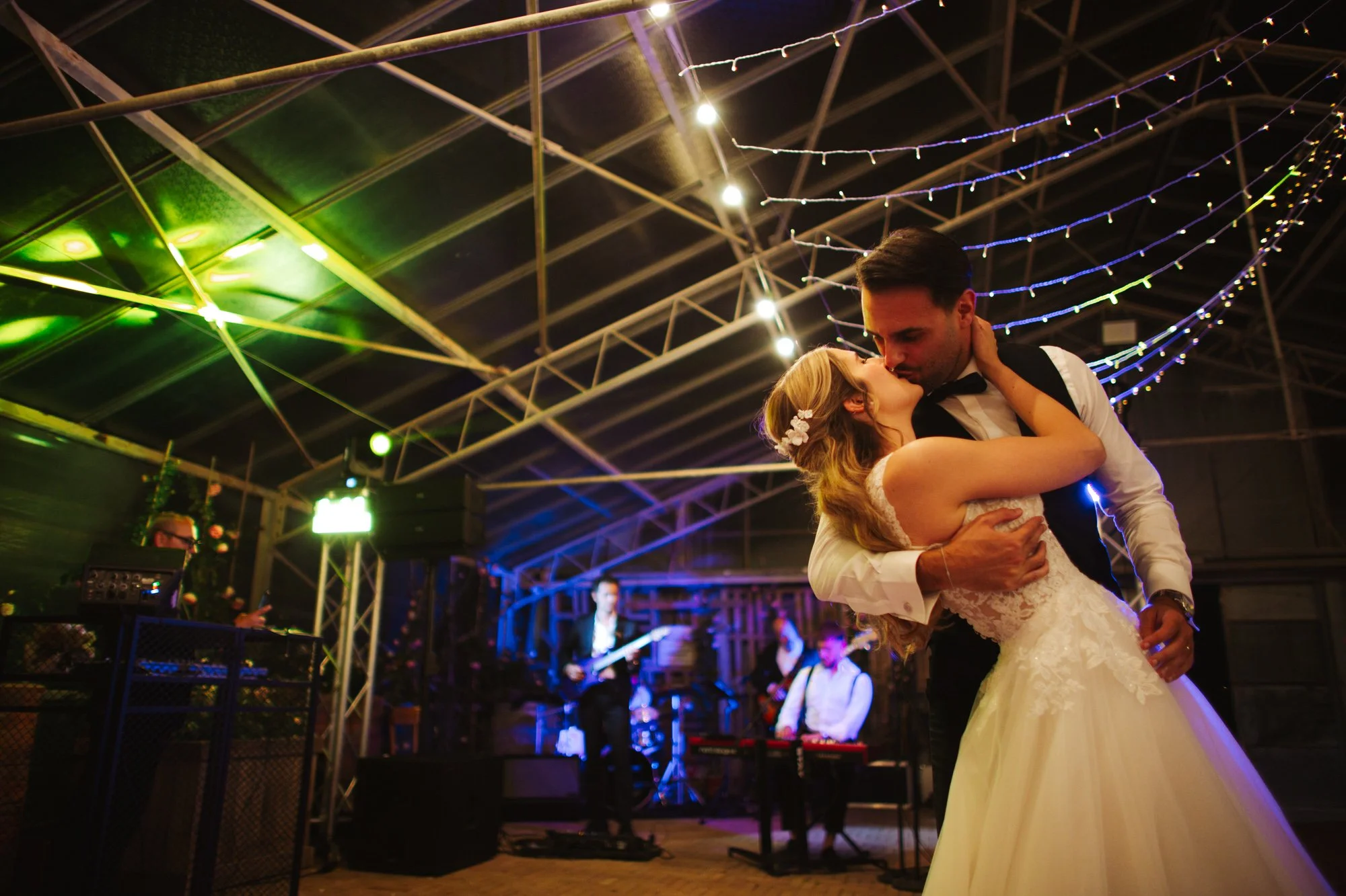 Lo sposo sostiene la sposa in una cascatella durante il loro primo ballo con la band che suona sullo sfondo